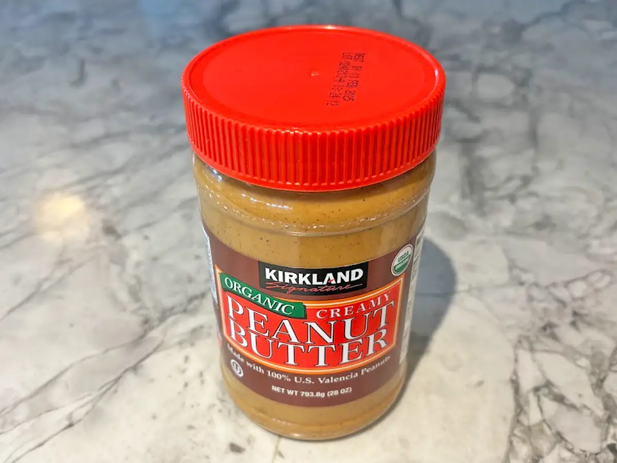 A large jar of peanut butter with a red and brown label and a red lid