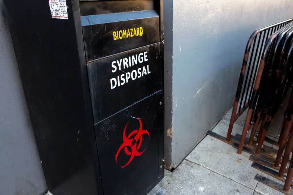 A black box with biohazard and syringe disposal written on it and a red biohazard symbol