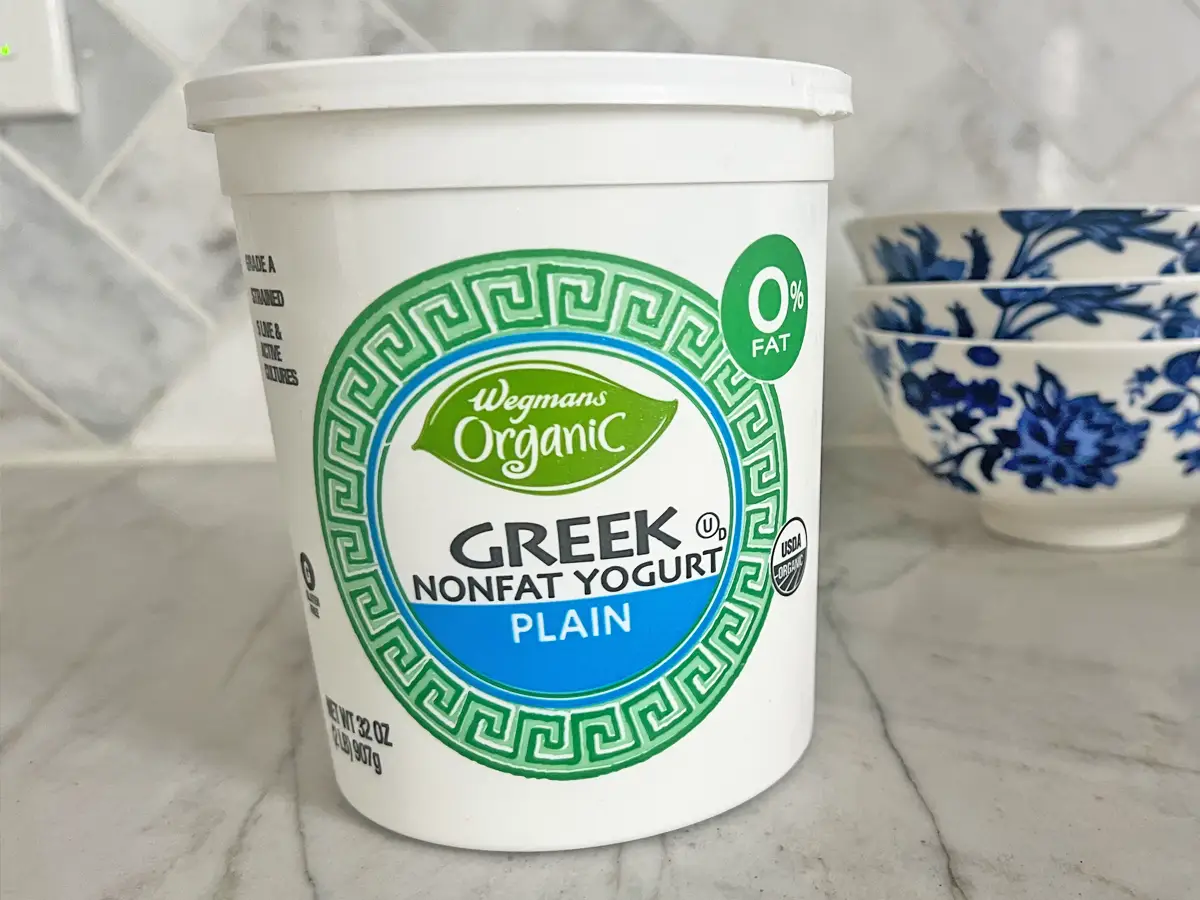 A white container with a green Greek key pattern in the shape of a circle, Wegmans organic logo, and text spelling out 