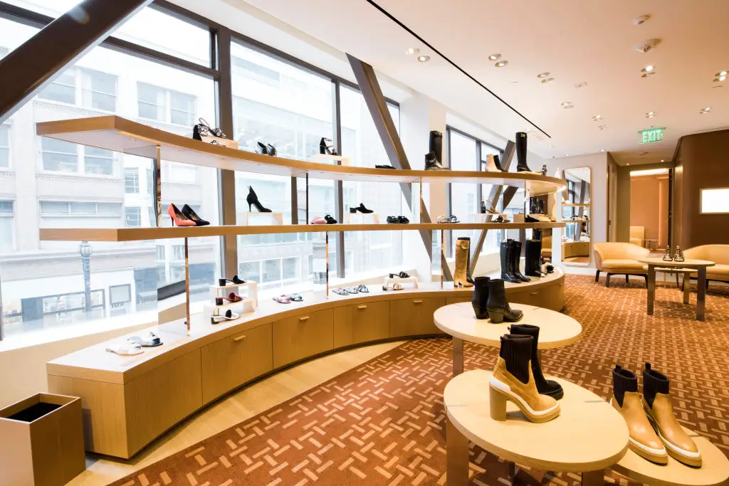 A curvy wooden shelf holding a shoe display at an Hermes store