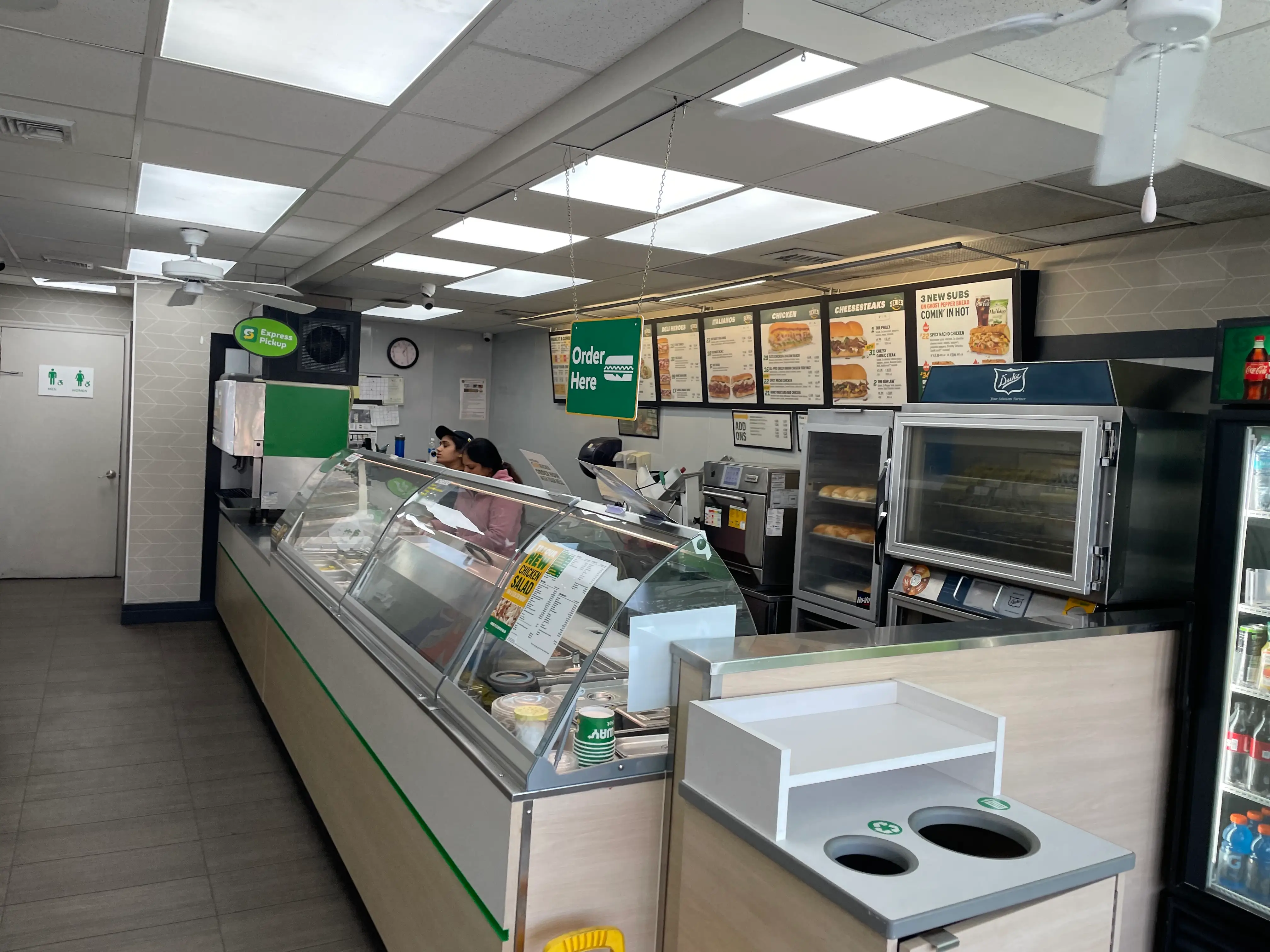 Workers behind the counter at a Subway sandwich shop.