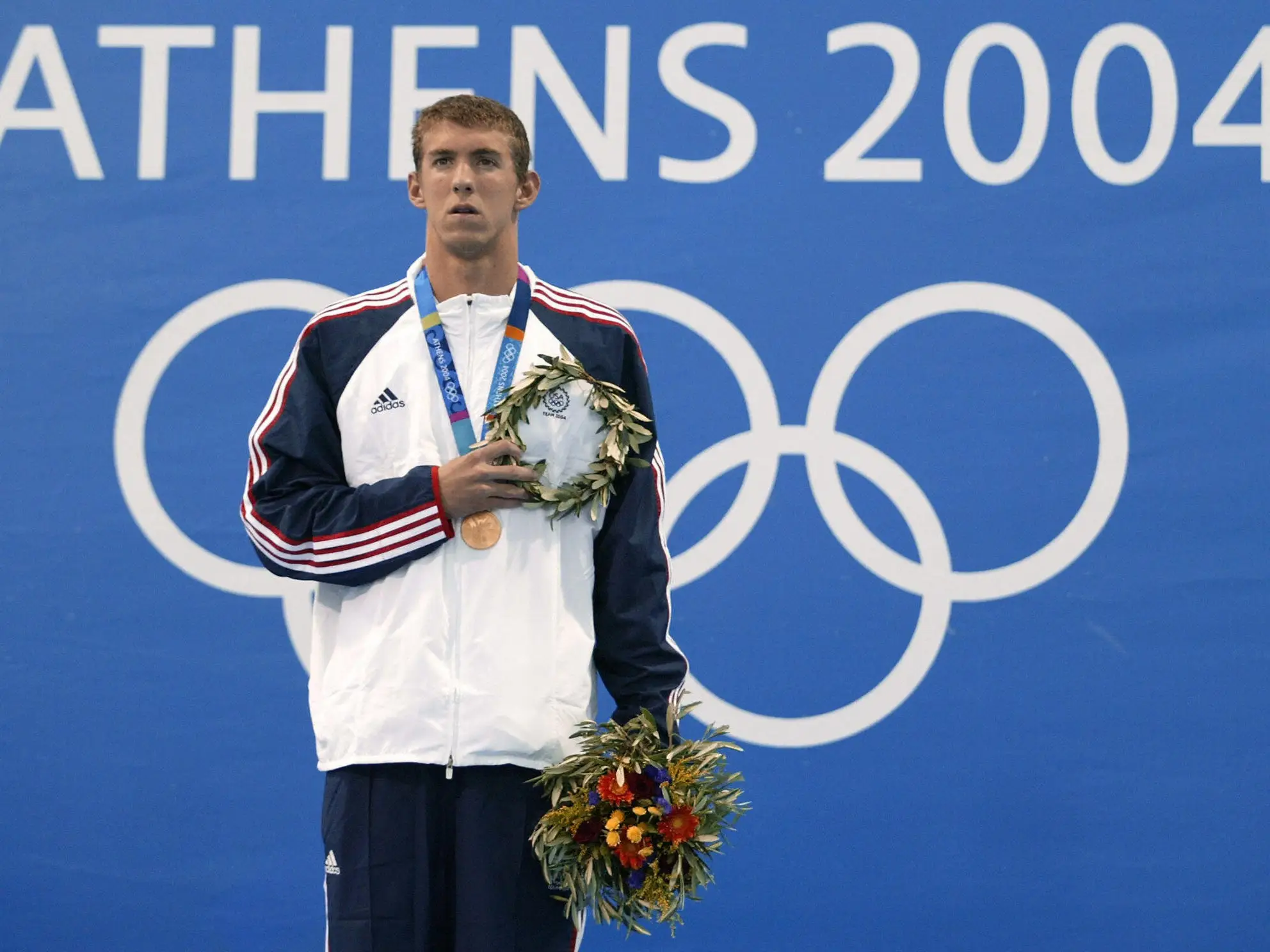 US Michael Phelps poses on the podium after winning the gold medal of the men's 400m individual medley final, at the 2004 Olympic Games at the Olympic Aquatic Center in Athens, 14 August 2004