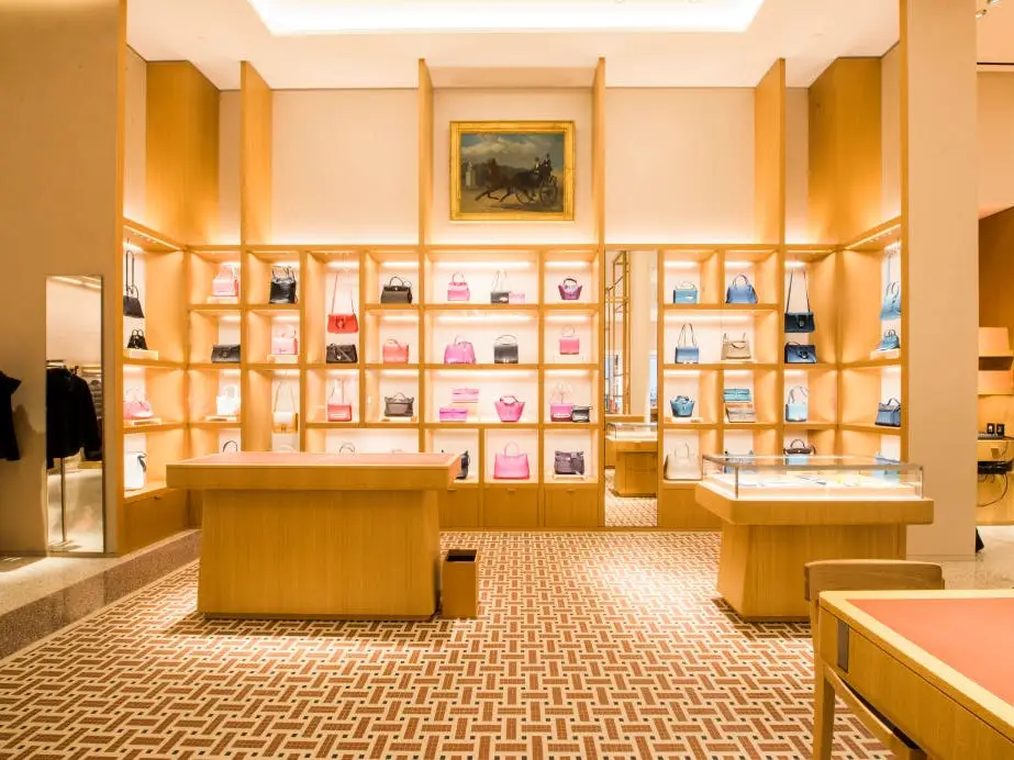 An Hermes store with a display of red, black, pink, and blue purses on shelves