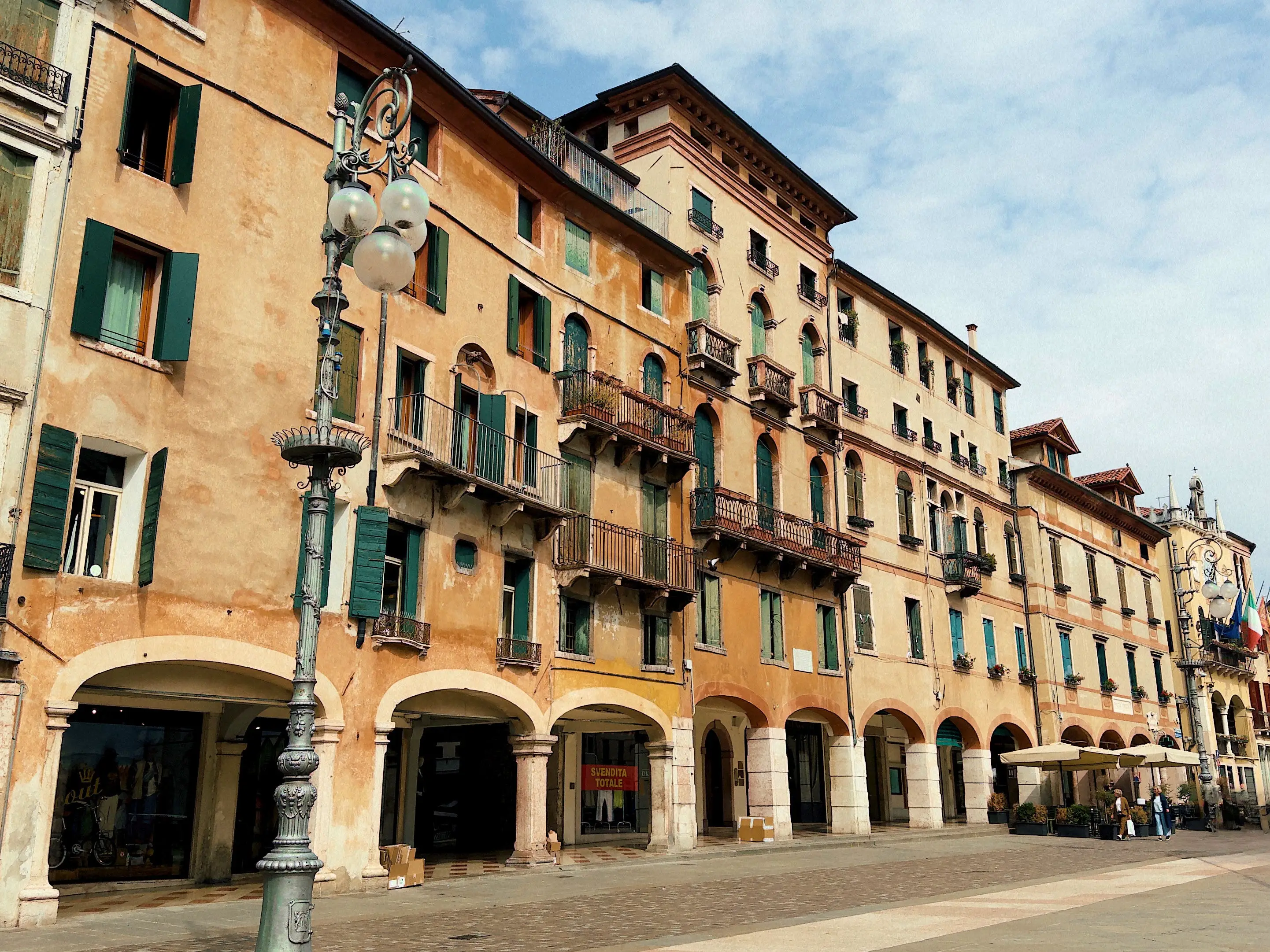 A row of old buildings with balconies on a street lined with light posts.