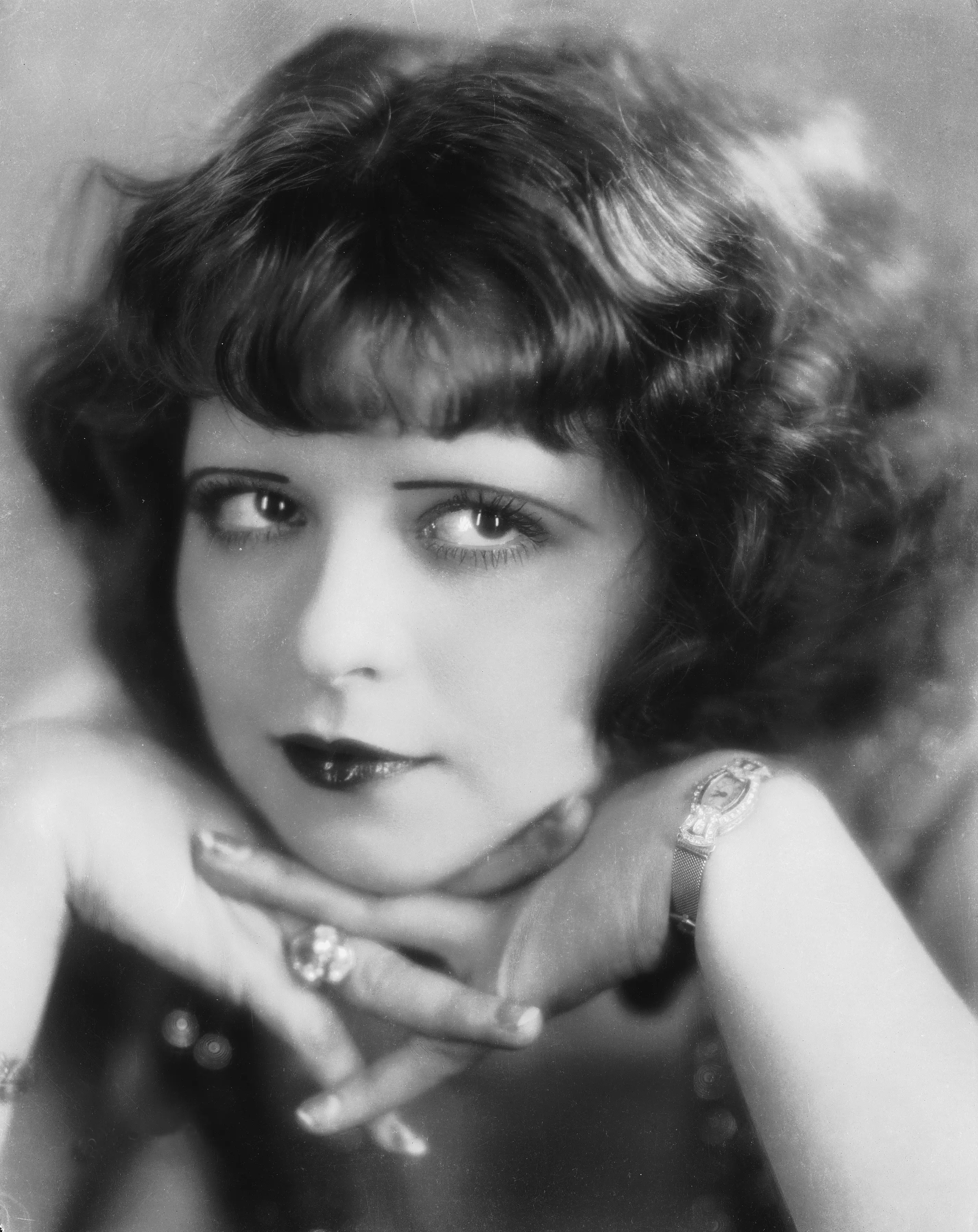 A photo of Clara Bow resting her head on her hands circa 1928.