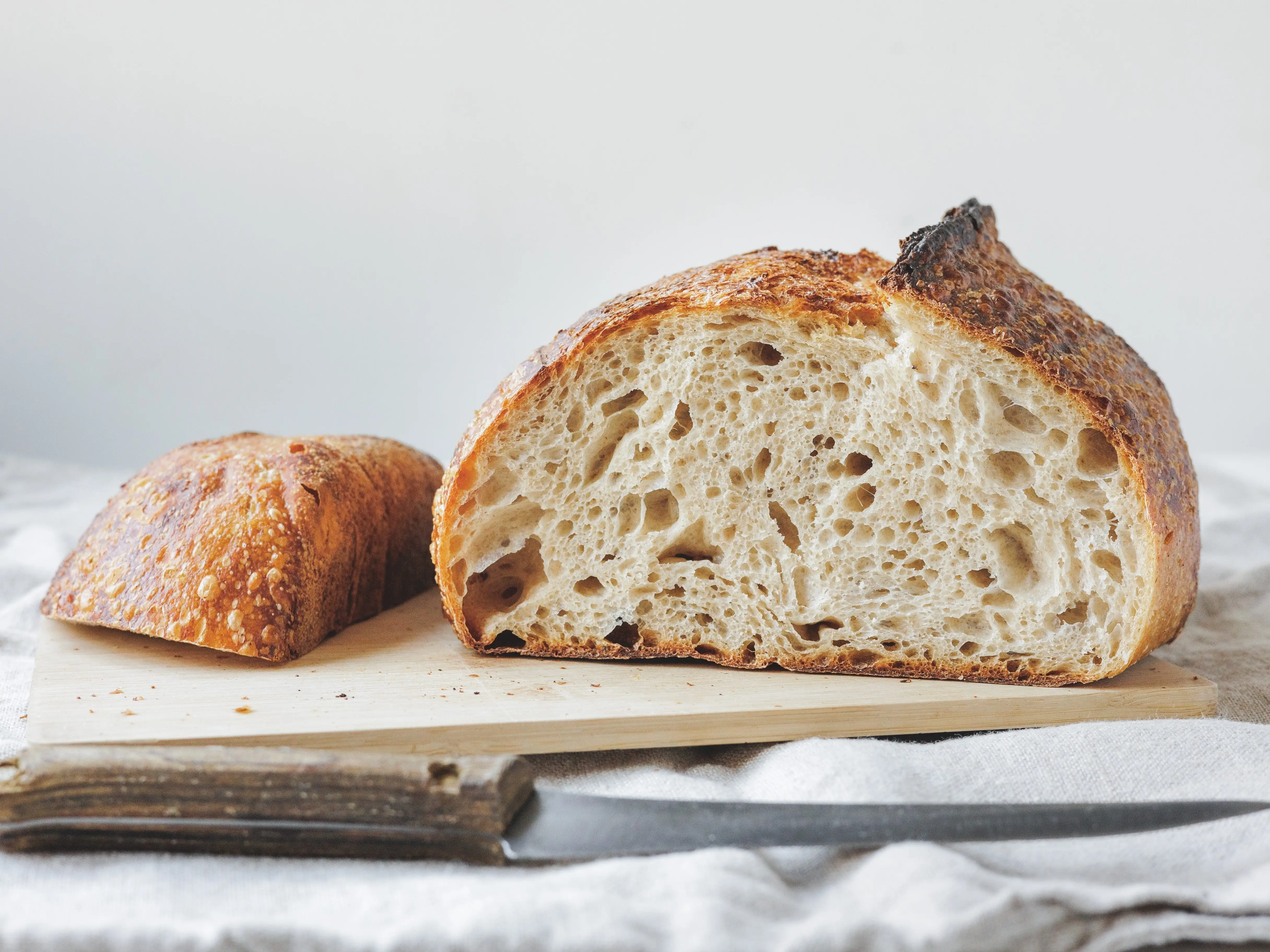 A sliced loaf of sourdough bread on a cutting board, with a knife next to it.