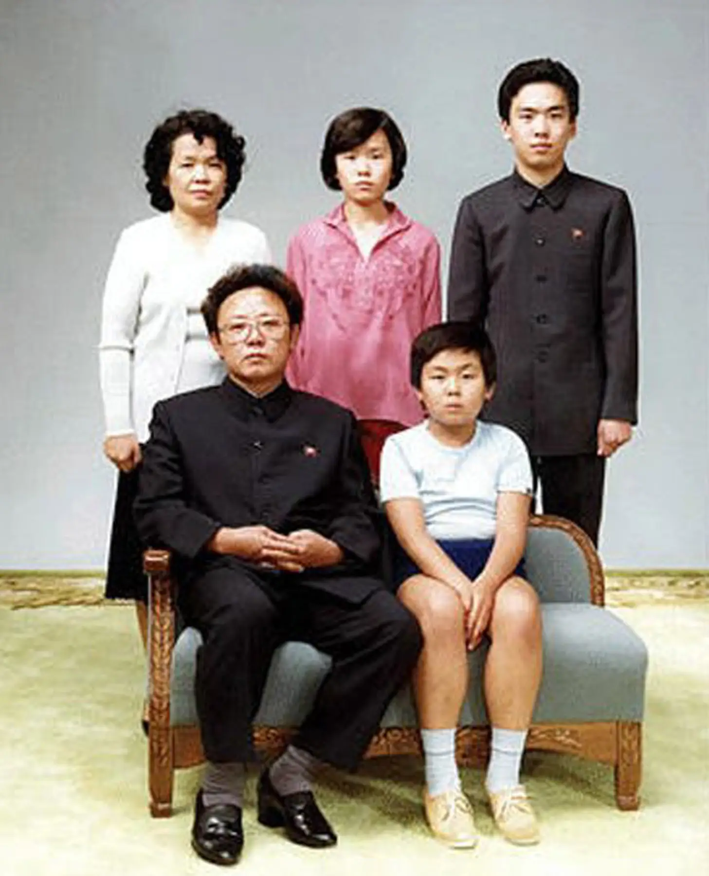 Kim Jong Il sits on a couch with his son Kim Jong Nam with three other family members standing behind them