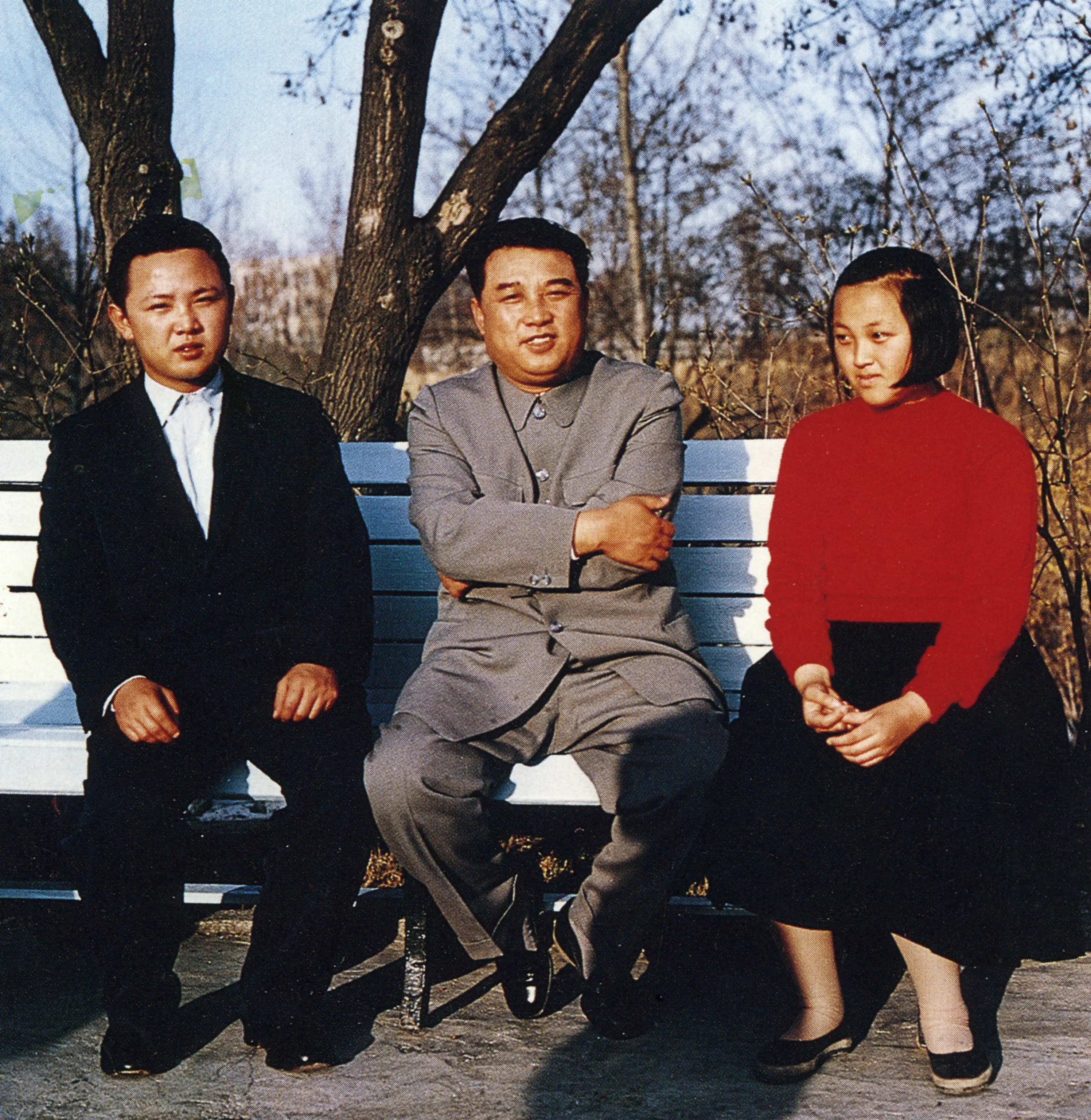 Kim Il Sung sits on a white park bench with his teenage children Kim Jong Il and Kim Kyong Hui