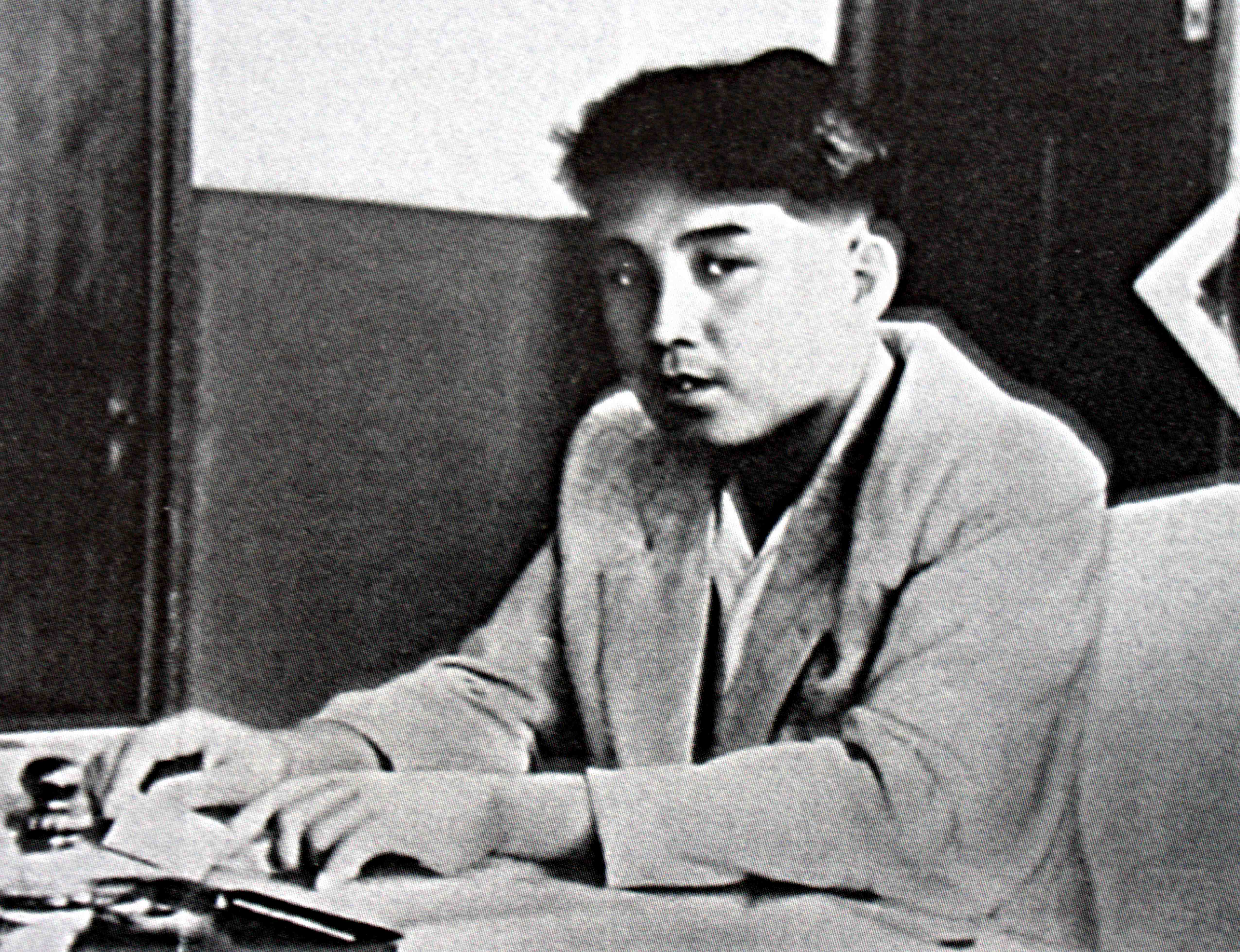 Kim Il Sung sits at a desk wearing a suit