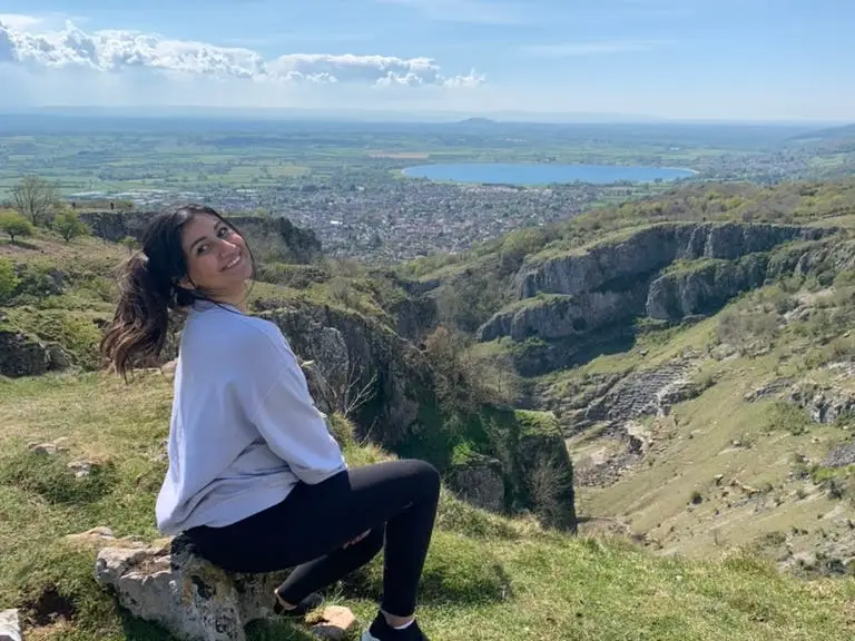 A woman poses in front of the Cheddar Gorge in the UK.