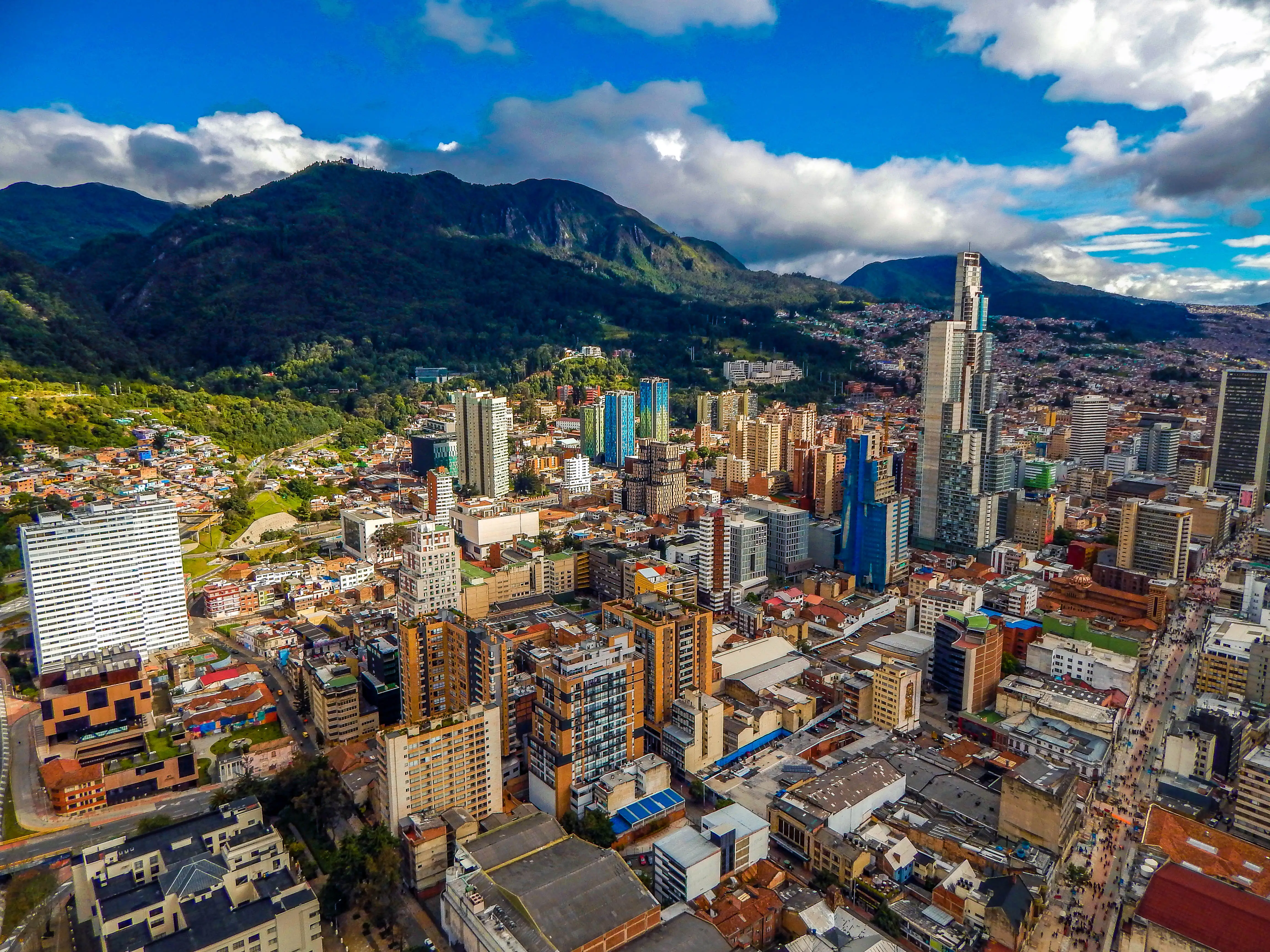 Bogota cityscape, the city sits below mountains and a bluee sky.