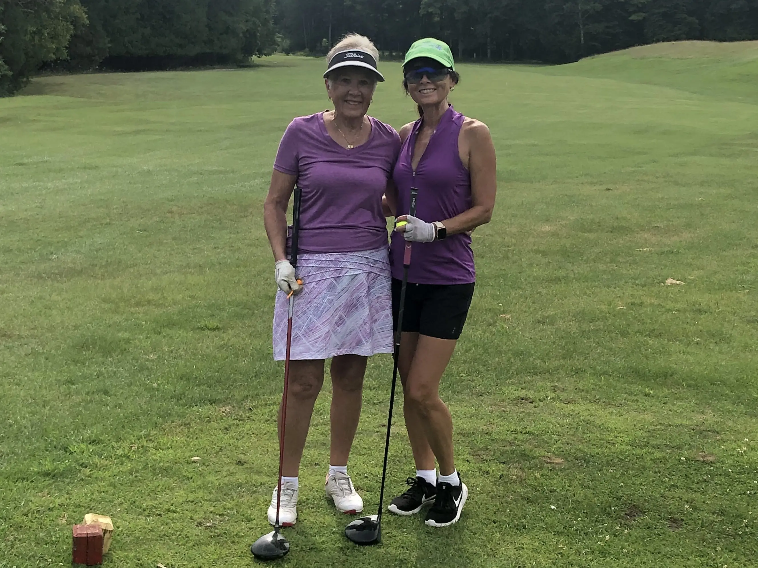 Janet Osborne and get mother standing side by side on golf course holding golf clubs