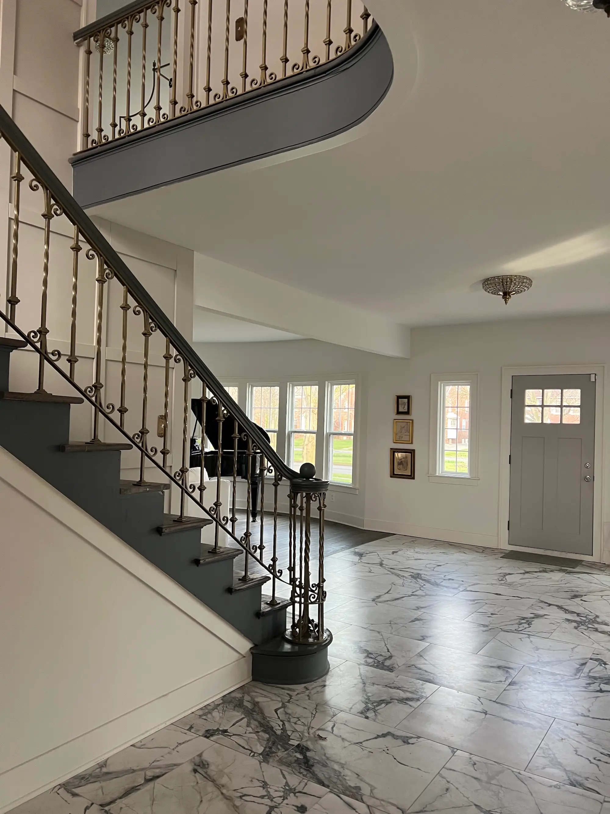 An entryway to a home with marble floors and a grand staircase.
