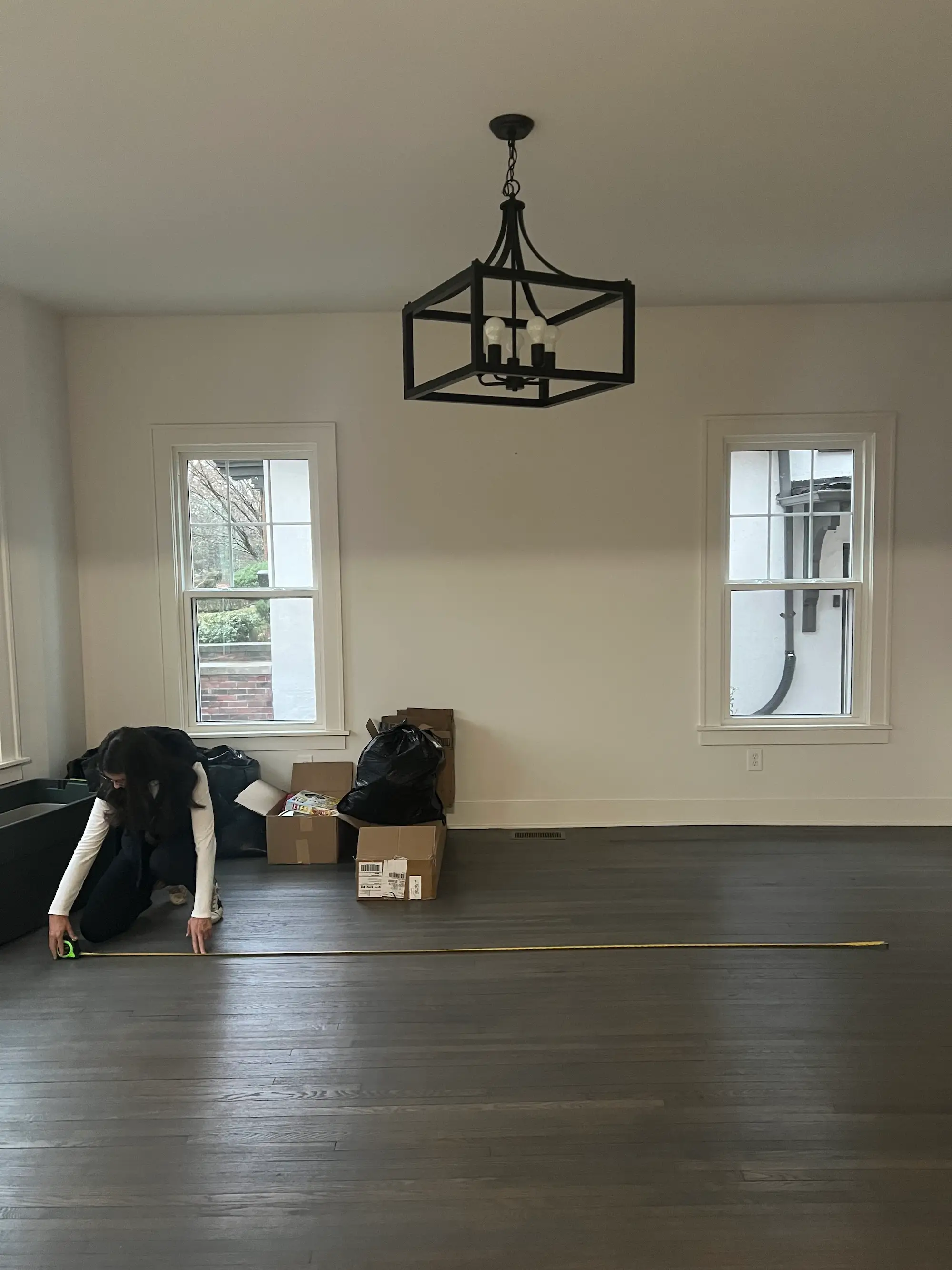 A dining room with sunny windows and a black chandelier.
