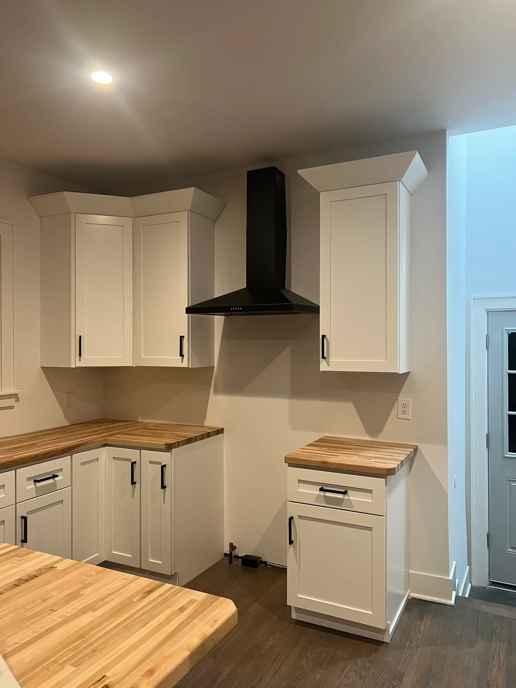 A kitchen with white cabinets and butcher block countertops.