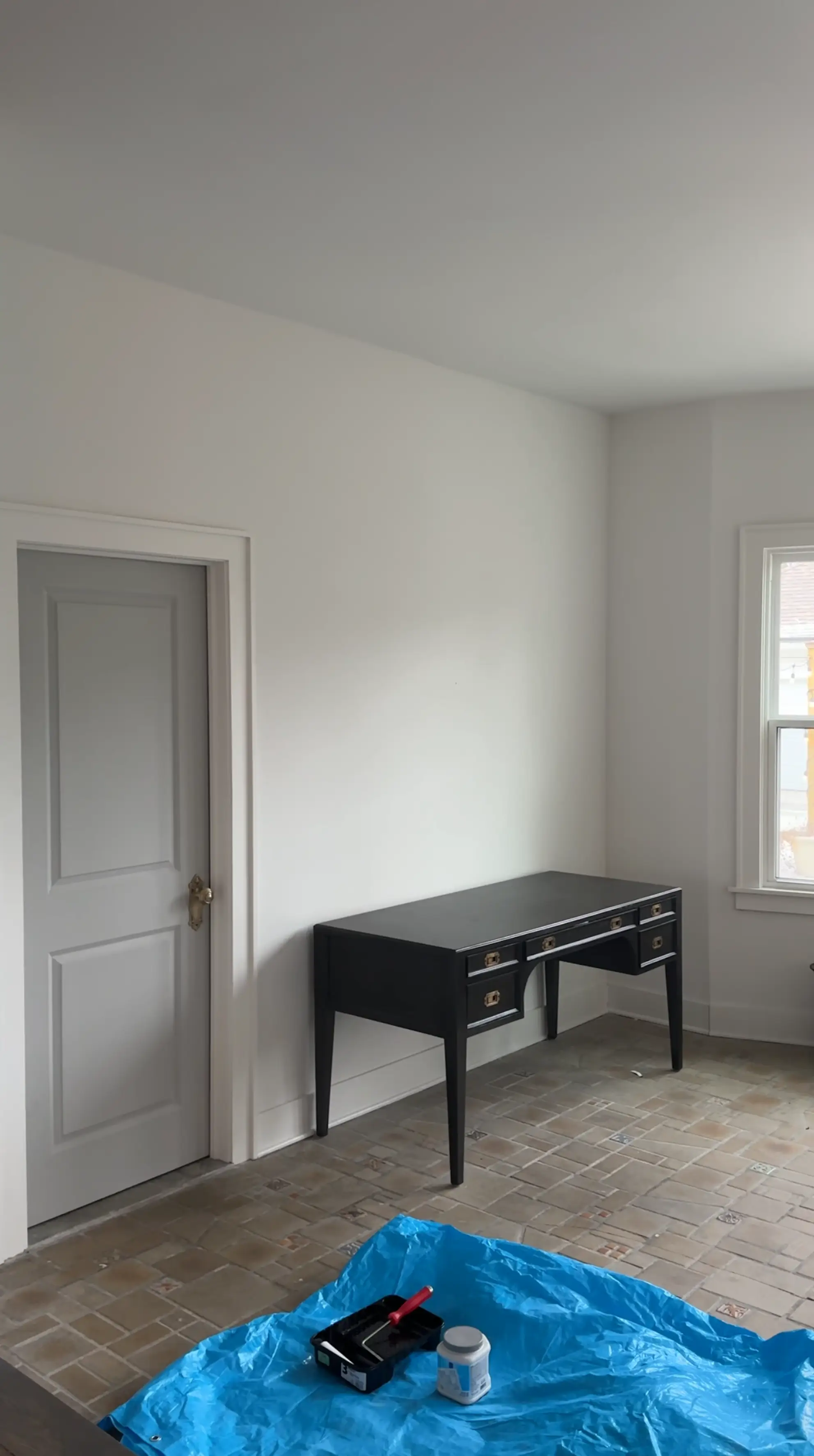 A room with white walls, a black desk, and tile floors.