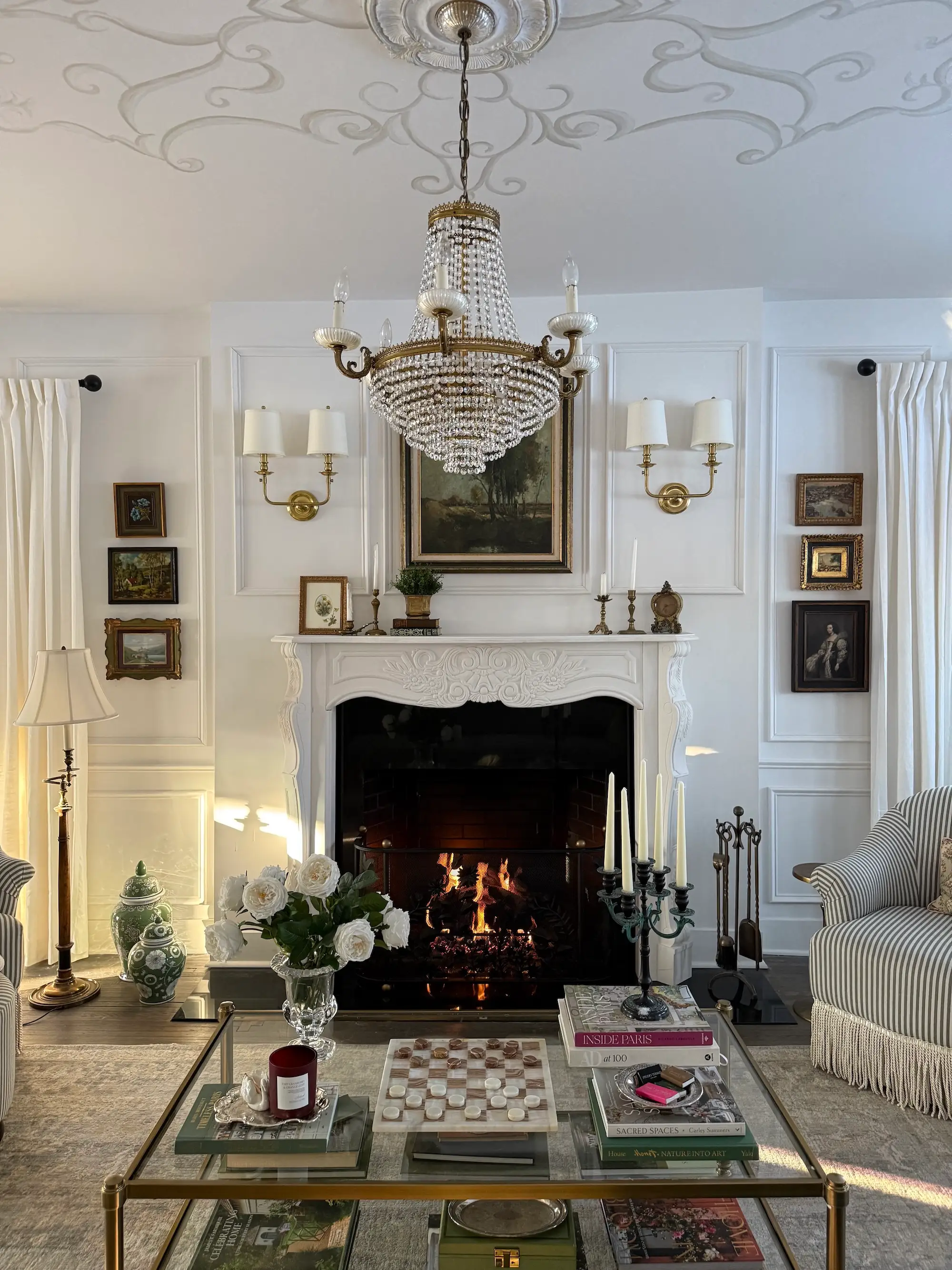 A living room with a white fireplace and gold light fixtures.