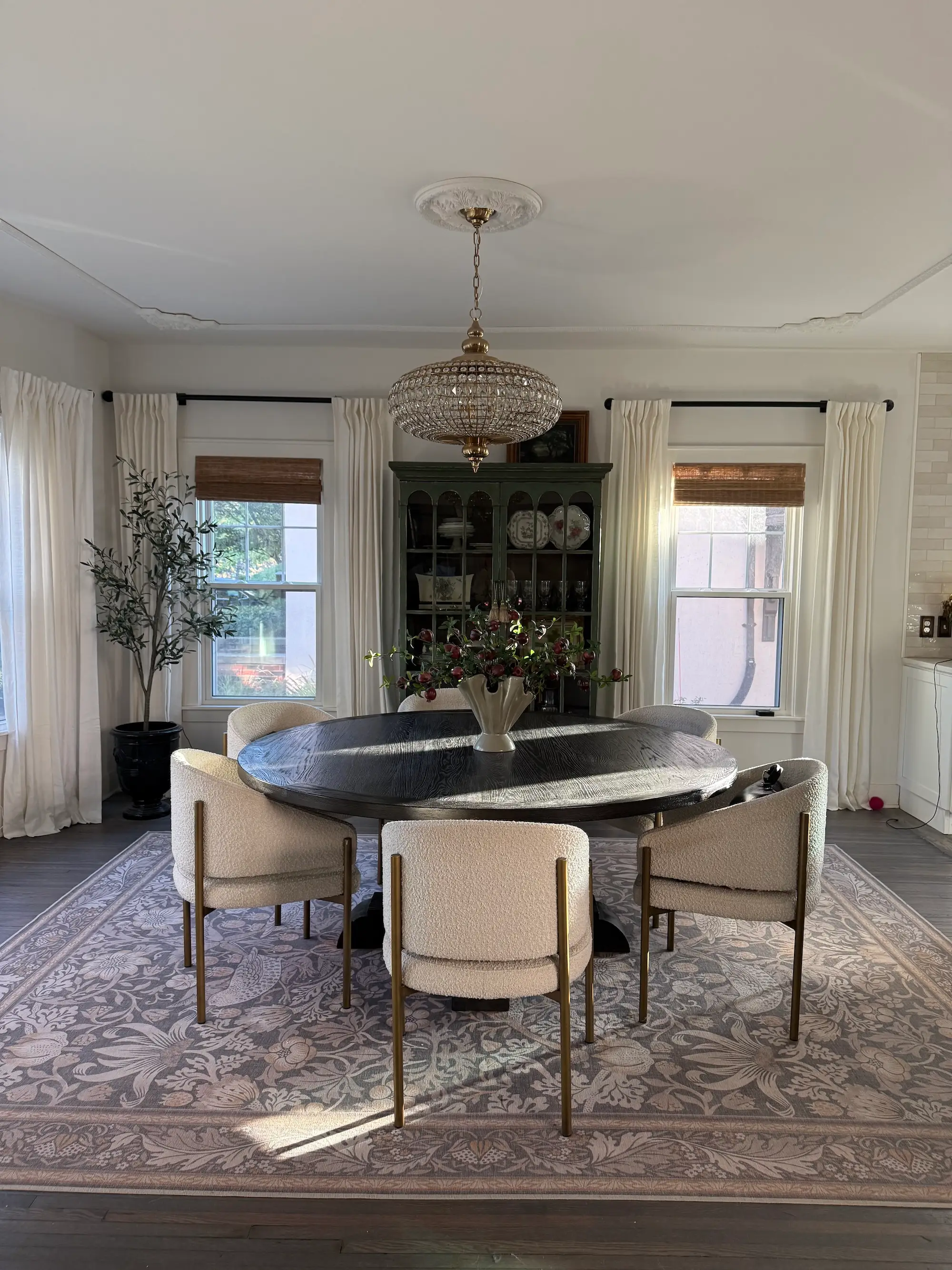 A dining room with a large, crystal chandelier, crown molding, and a round table.