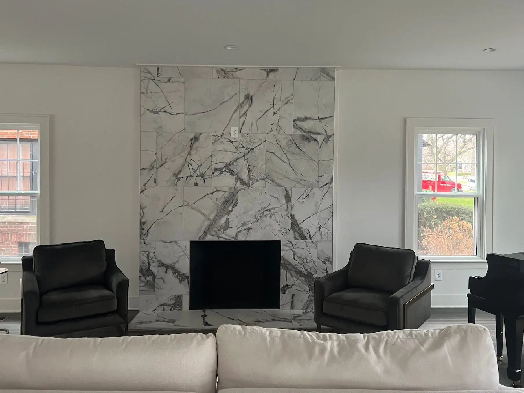 A living room with a marble fireplace and white walls.