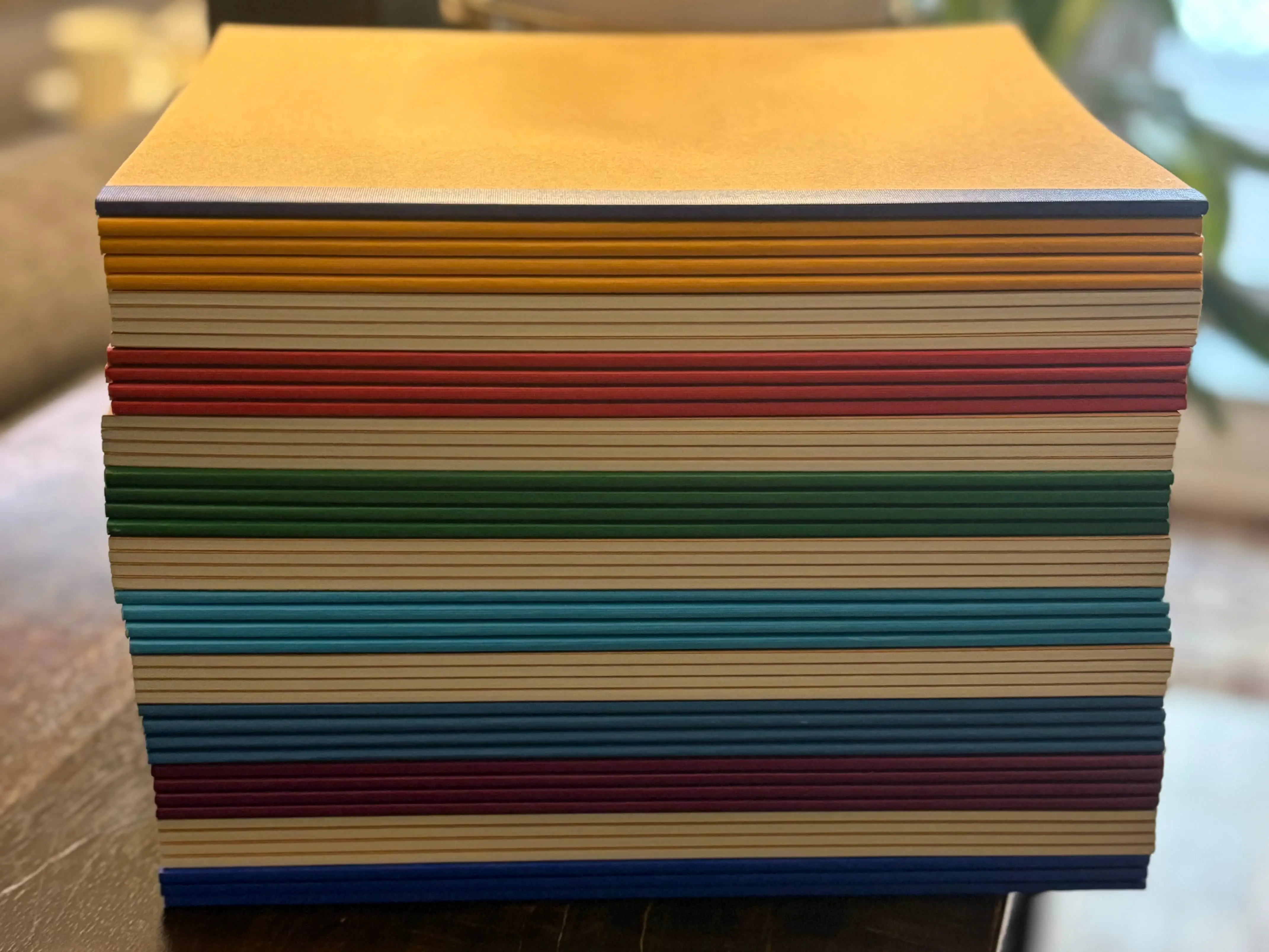 A stack of colorful notebooks from Amazon on top of a wooden table.