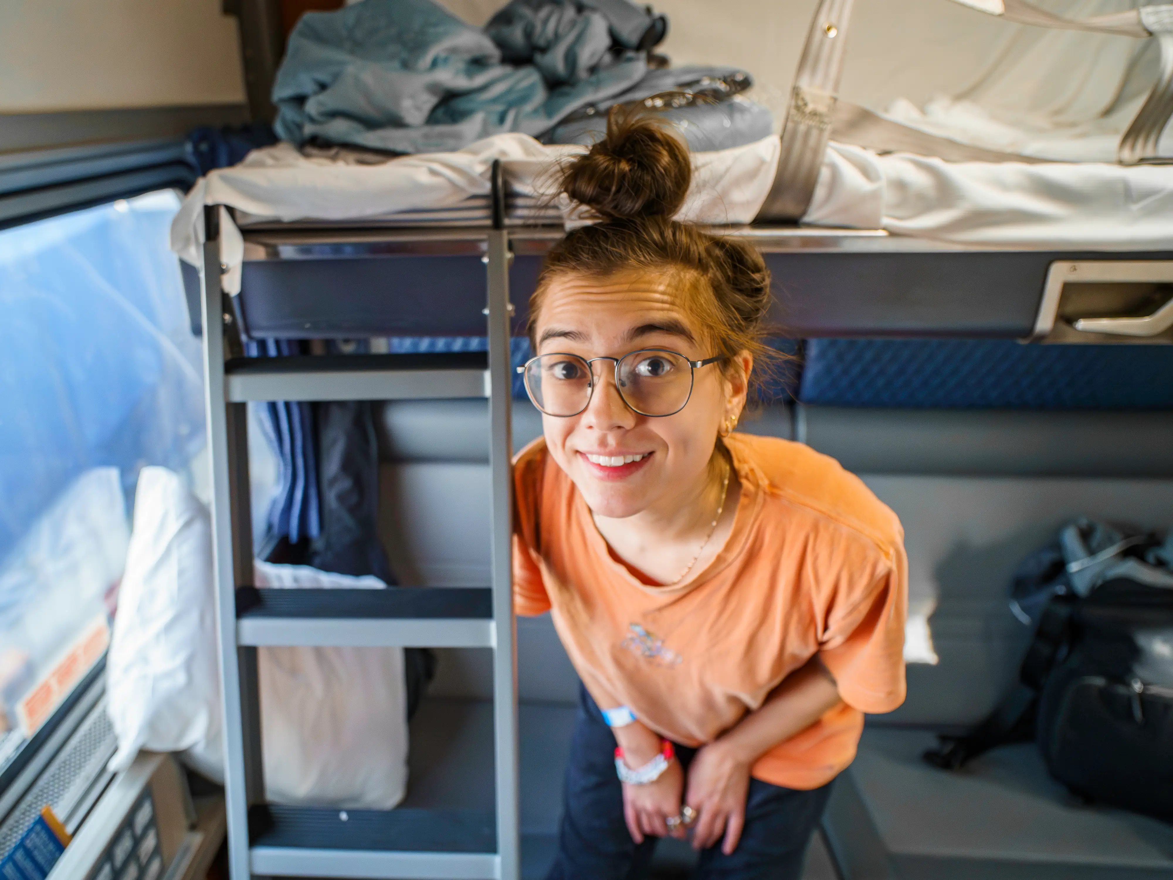 The author standing smiling in the Amtrak bedroom with a bunk bed in the background