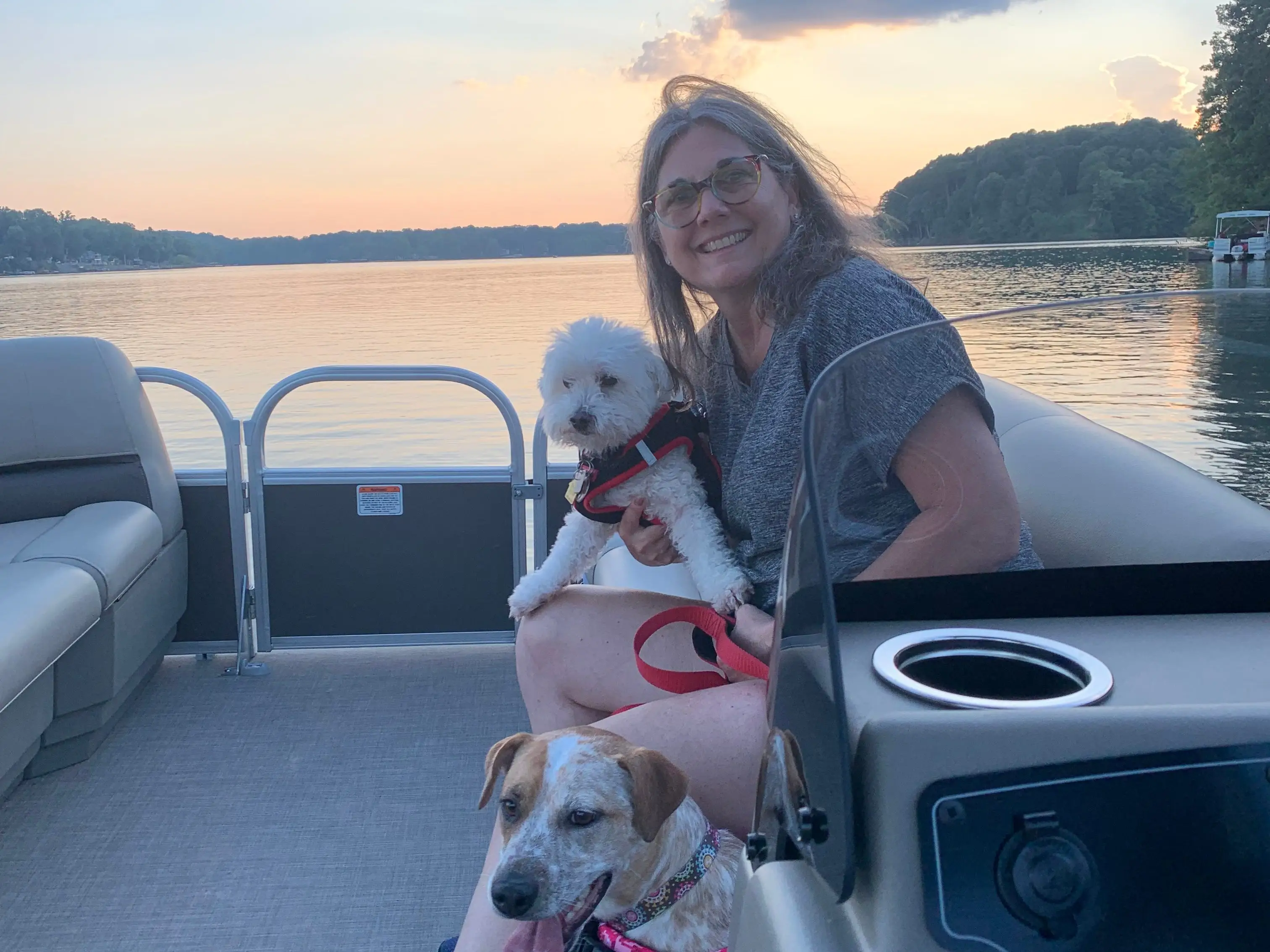 A woman holds a dog as she sits on a boat.