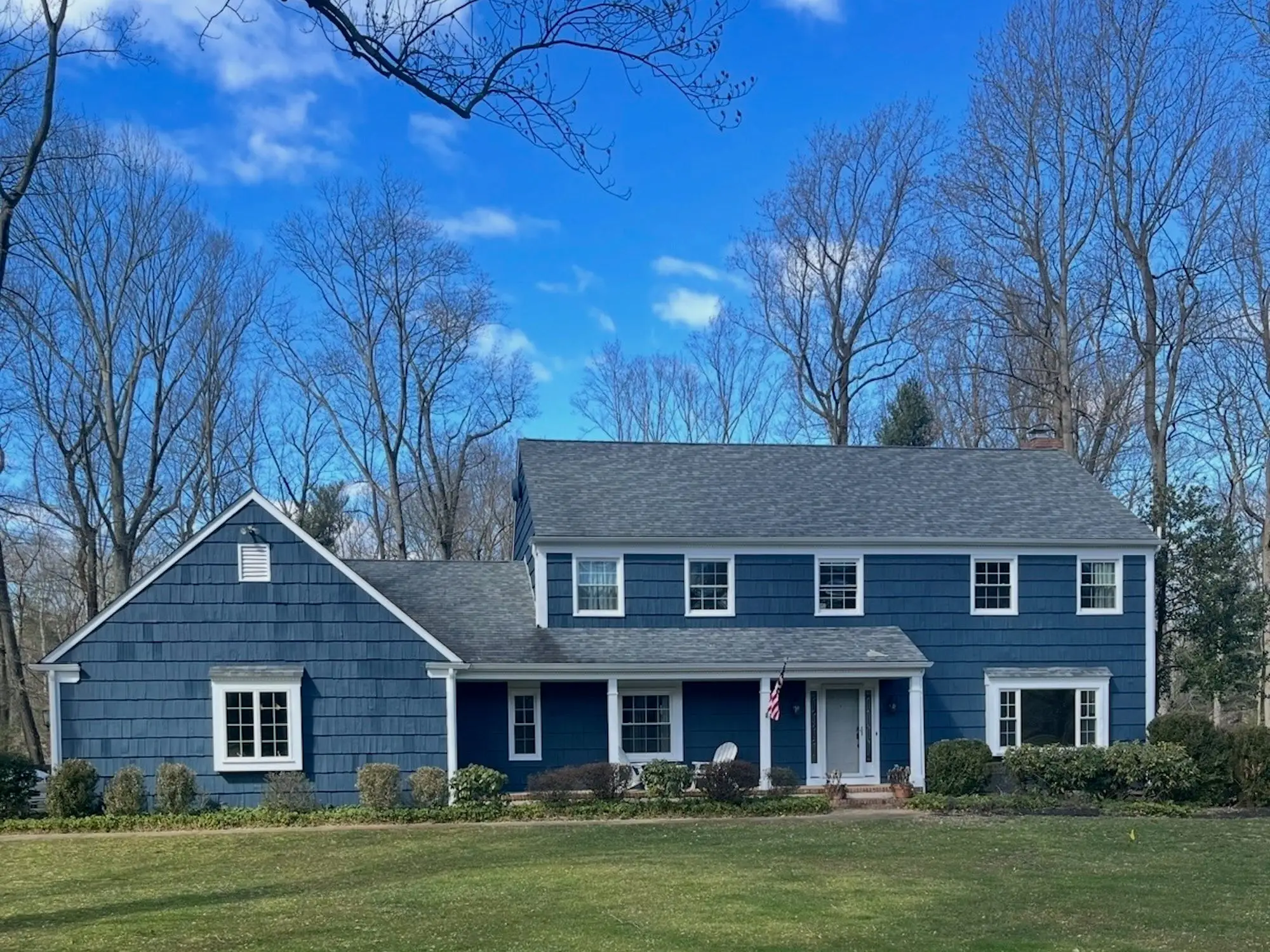 A blue house with a green lawn in front of it.