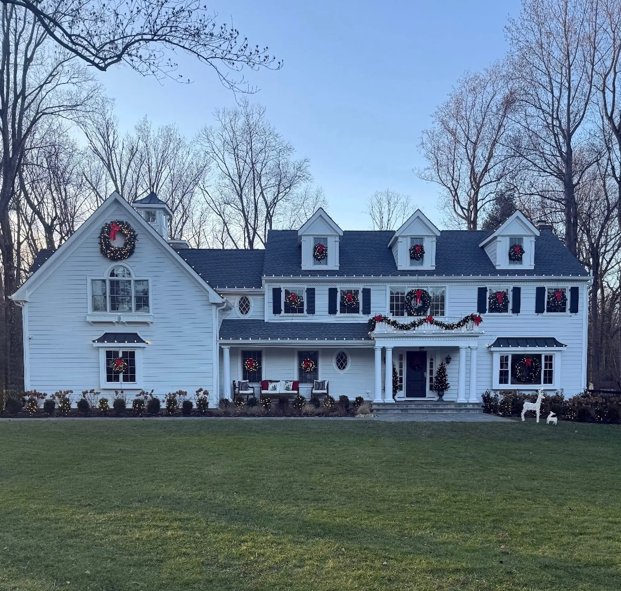 A white house with a green lawn decorated for Christmas.