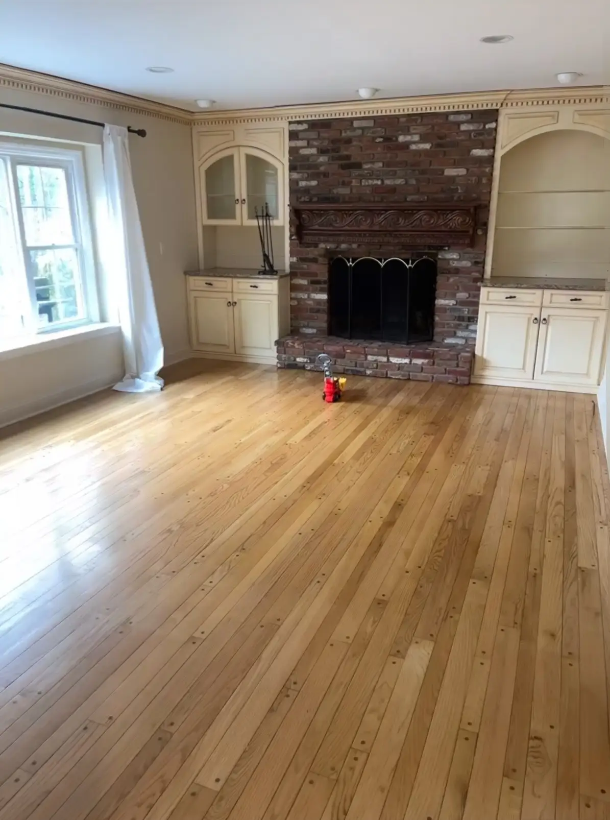 A living room with a brick fireplace and built-in bookshelves.