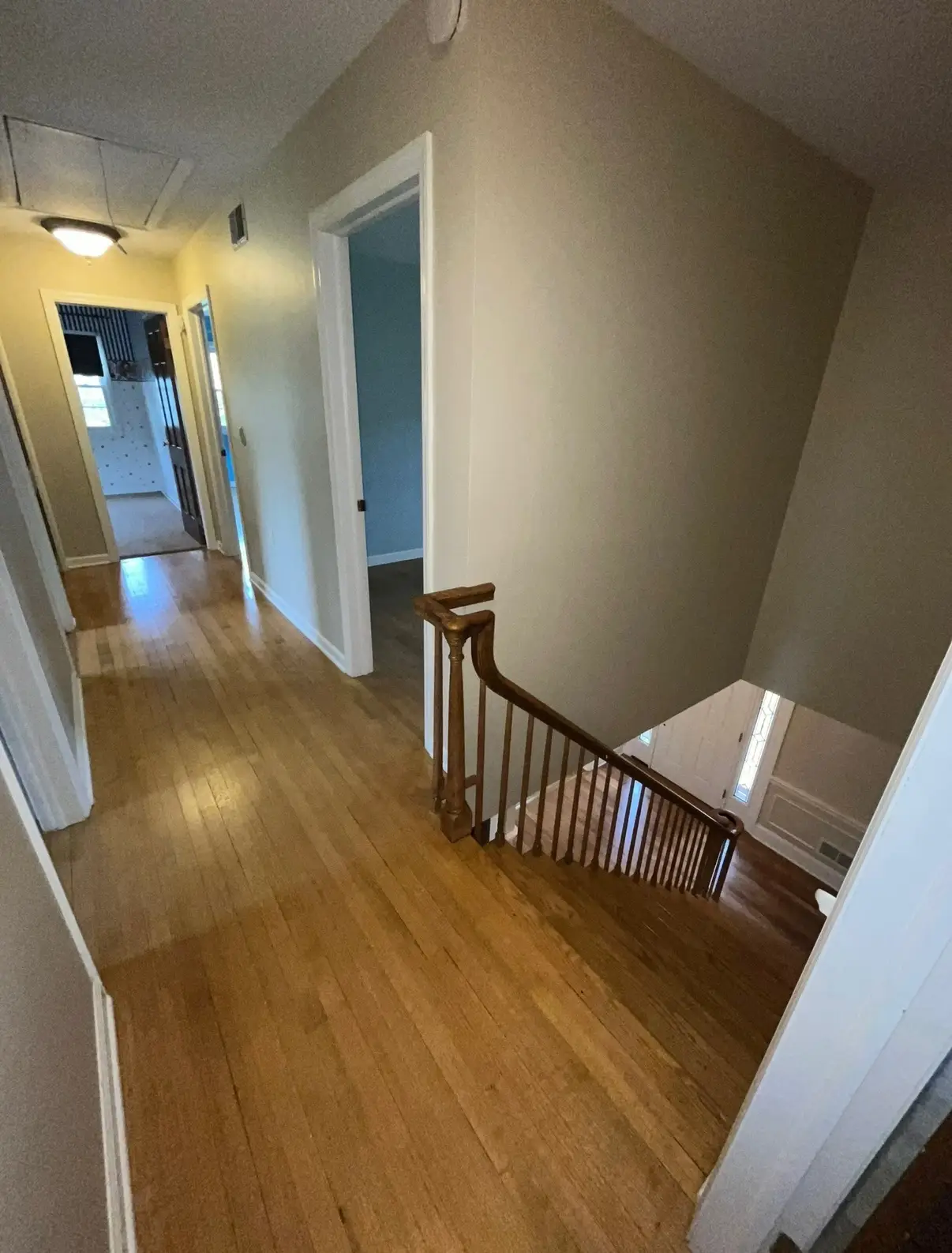 A hallway with a staircase leading downstairs.