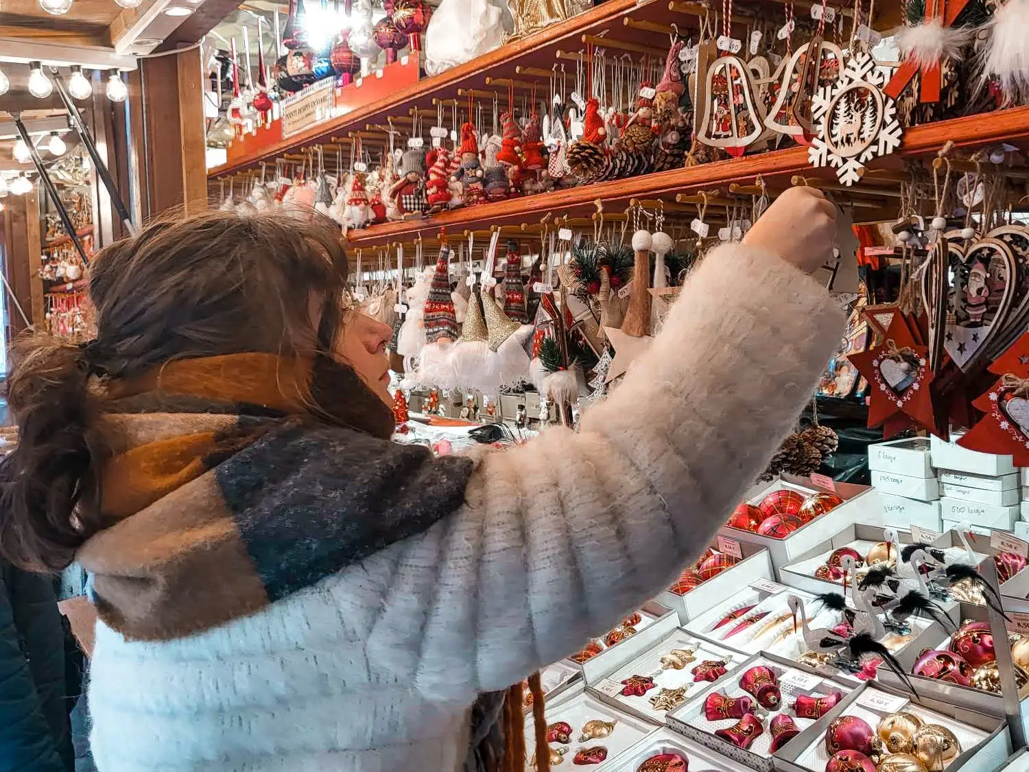 A woman reaches for an ornament in a Christmas market.