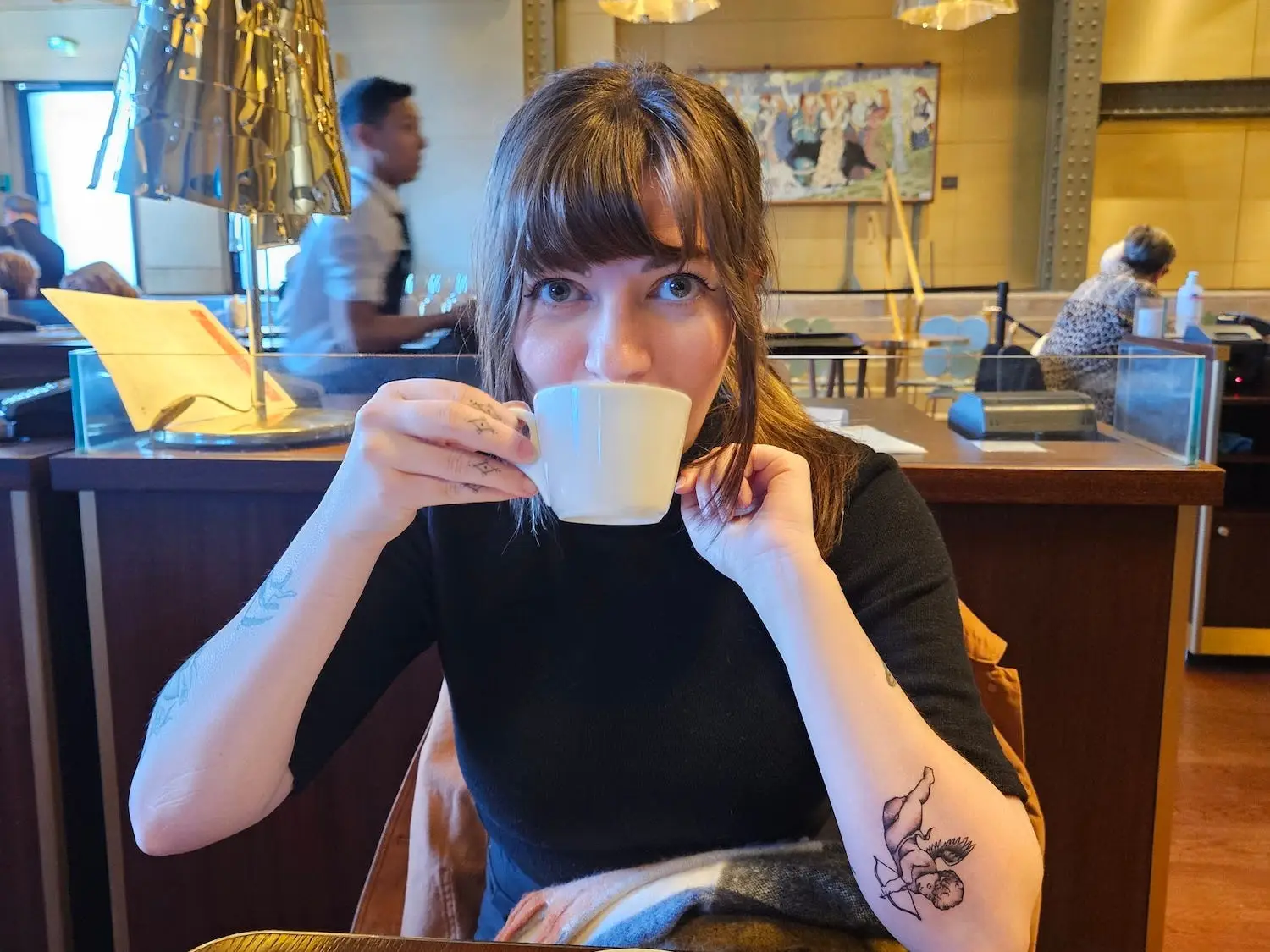 A woman drinks from a coffee cup.