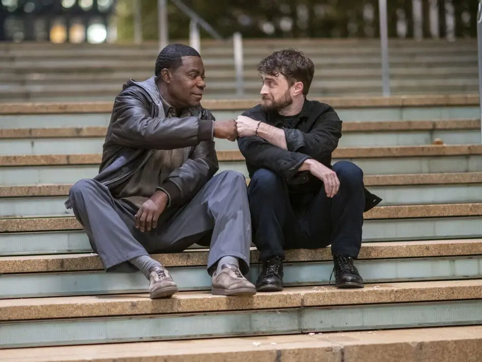 Tracy Morgan and Daniel Radcliffe pounding it while sitting on steps in The Fall and Rise of Reggie Dinkins
