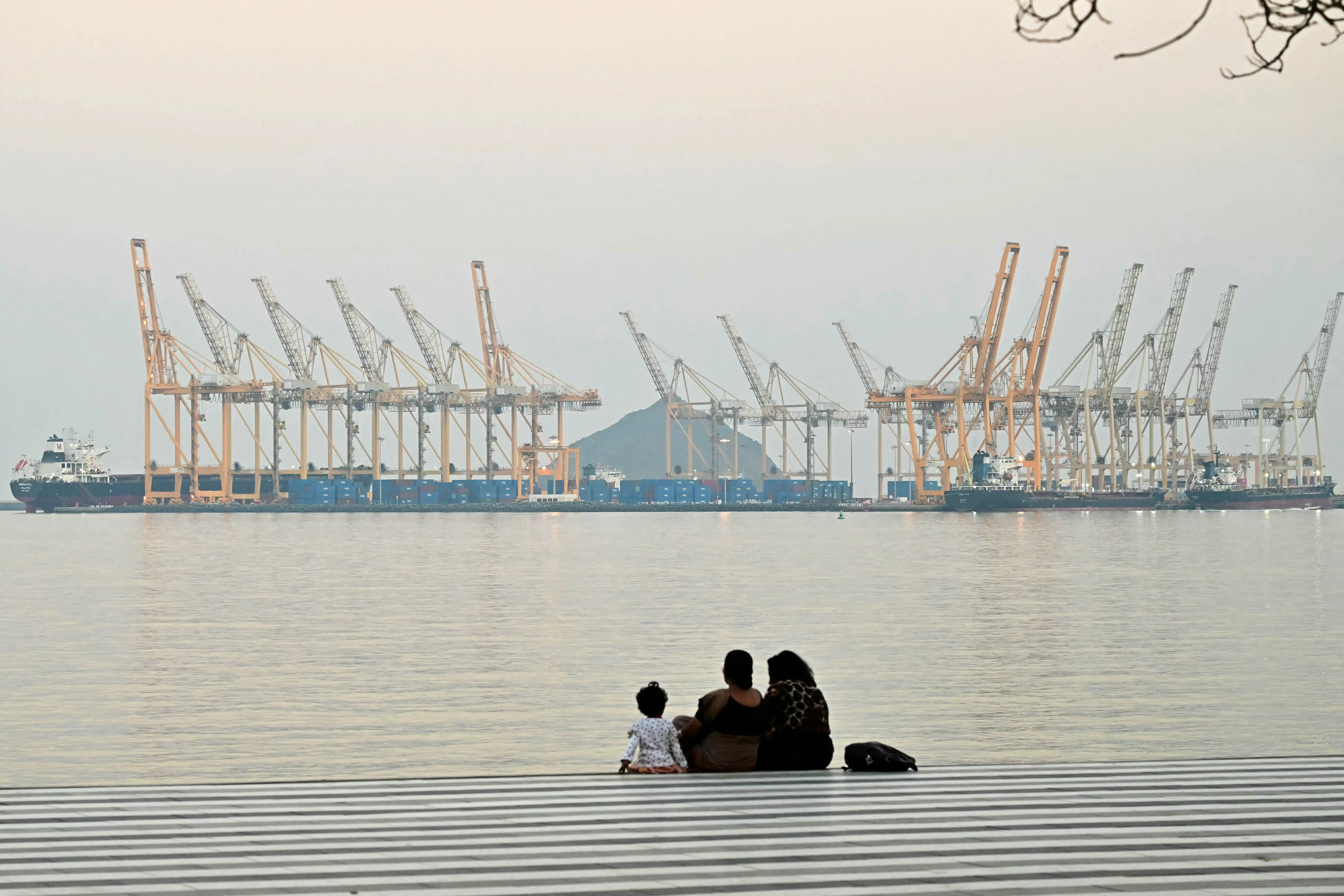 A family sits against the backdrop of a dockyard off coast city of Fujairah.