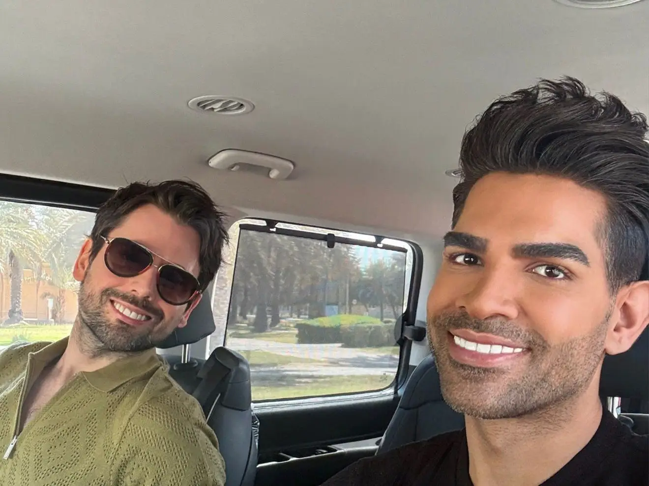 Two men posing for photo inside a car