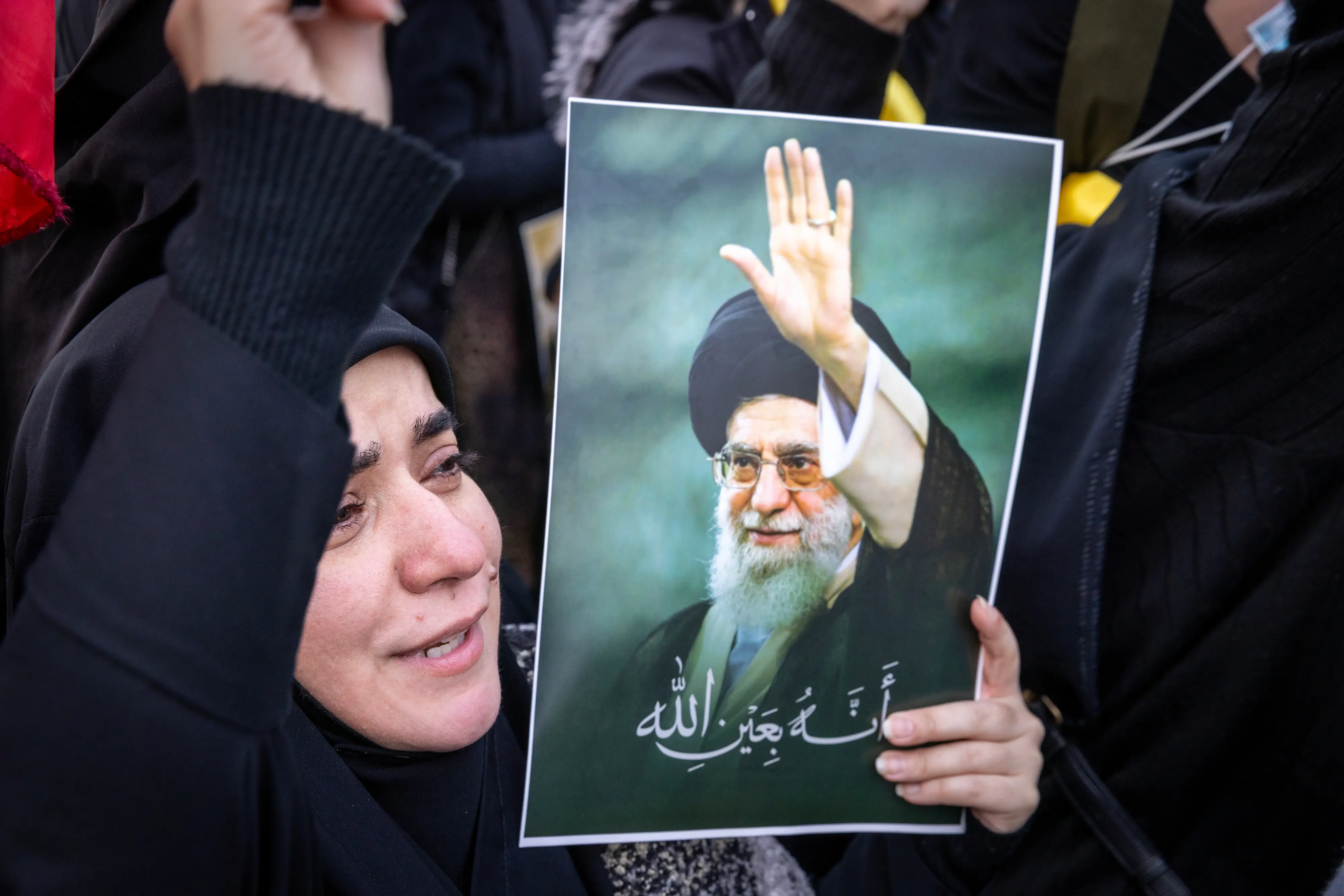 A woman in Beirut cries while holding a picture Iran's former Supreme Leader, Ayatollah Ali Khamenei.
