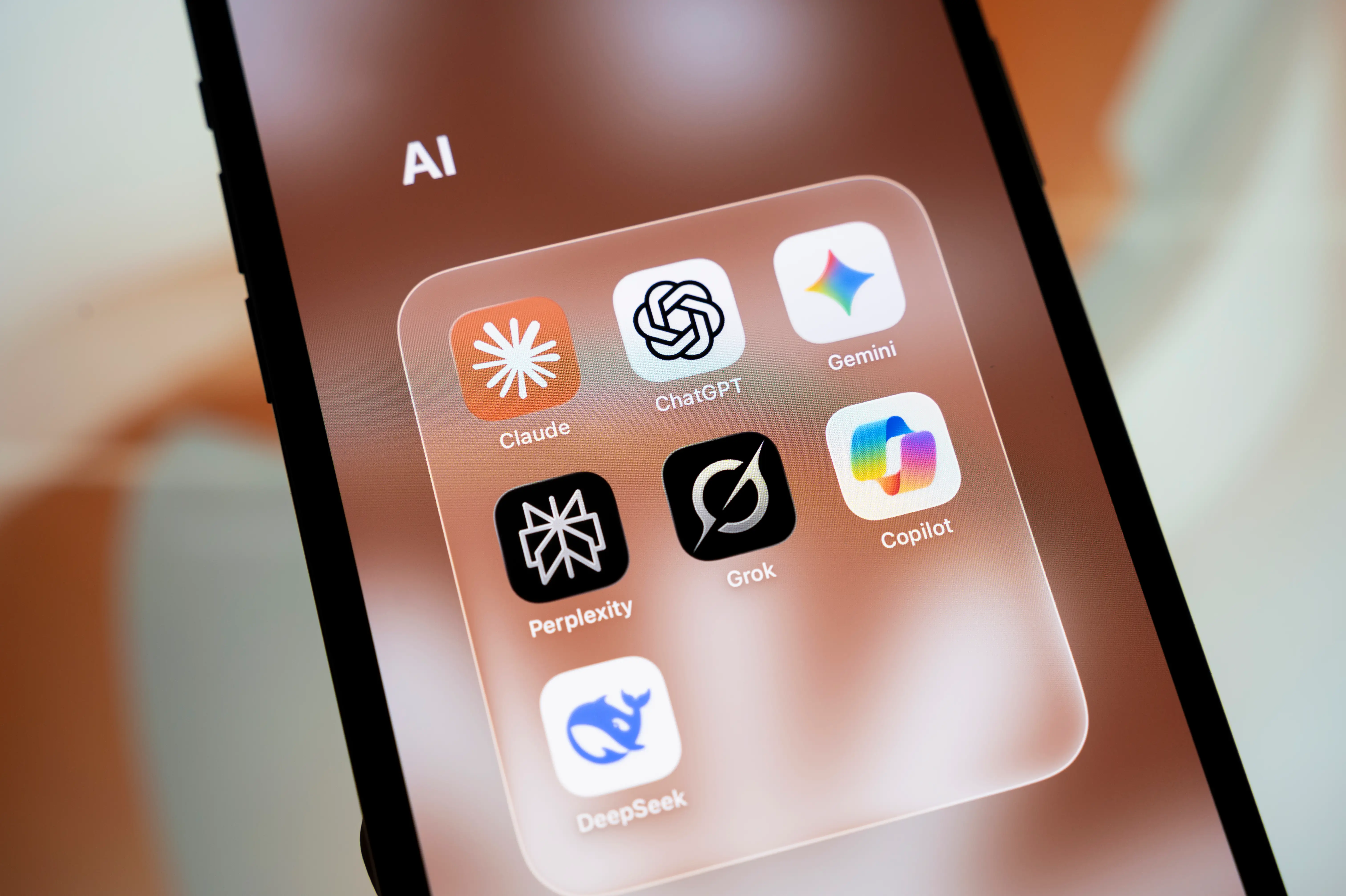 A folder with AI apps including Claude, ChatGPT, and Gemini is pictured.