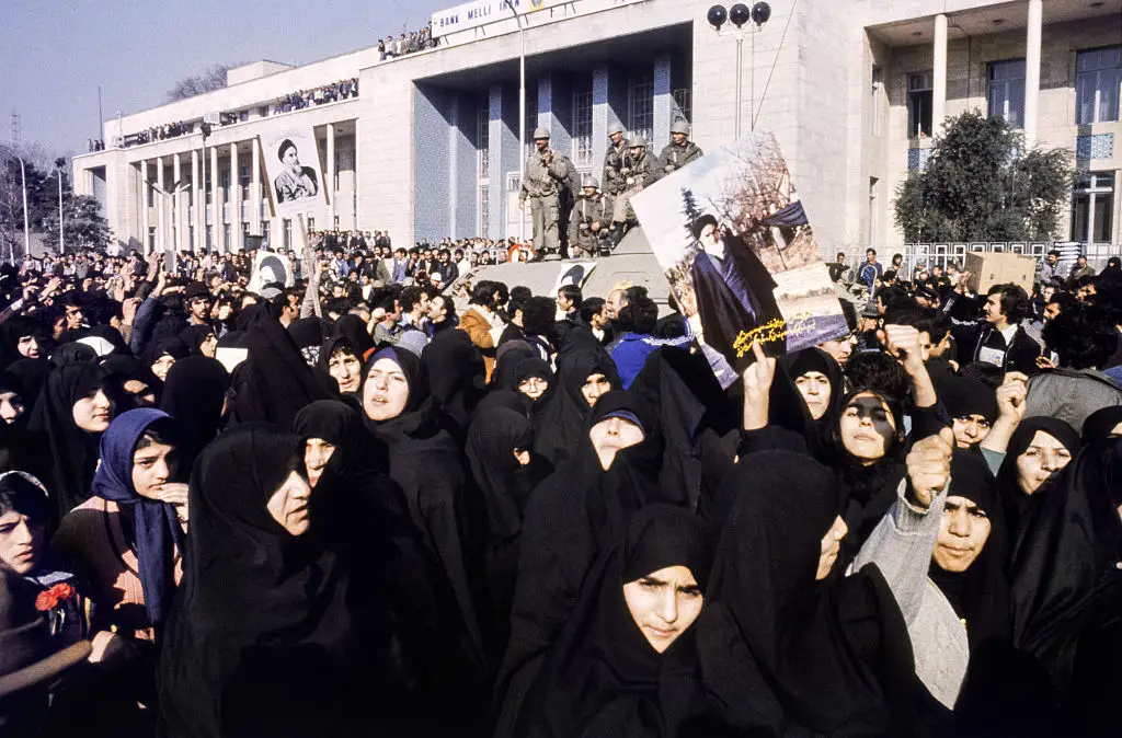 Iranian women hold a portrait of Ayatollah Khomeini.