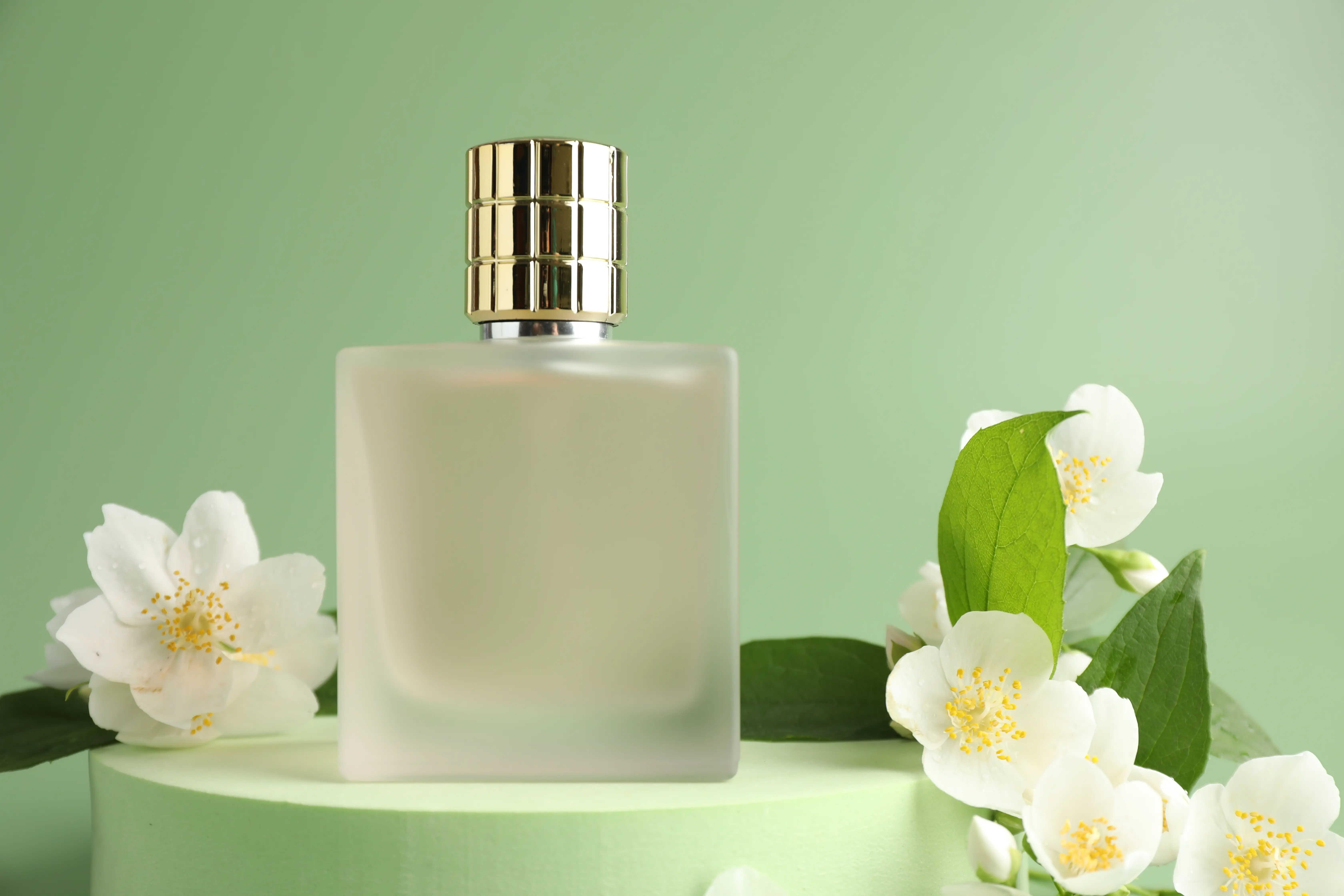 A perfume bottle surrounded by white flowers, with a green background.