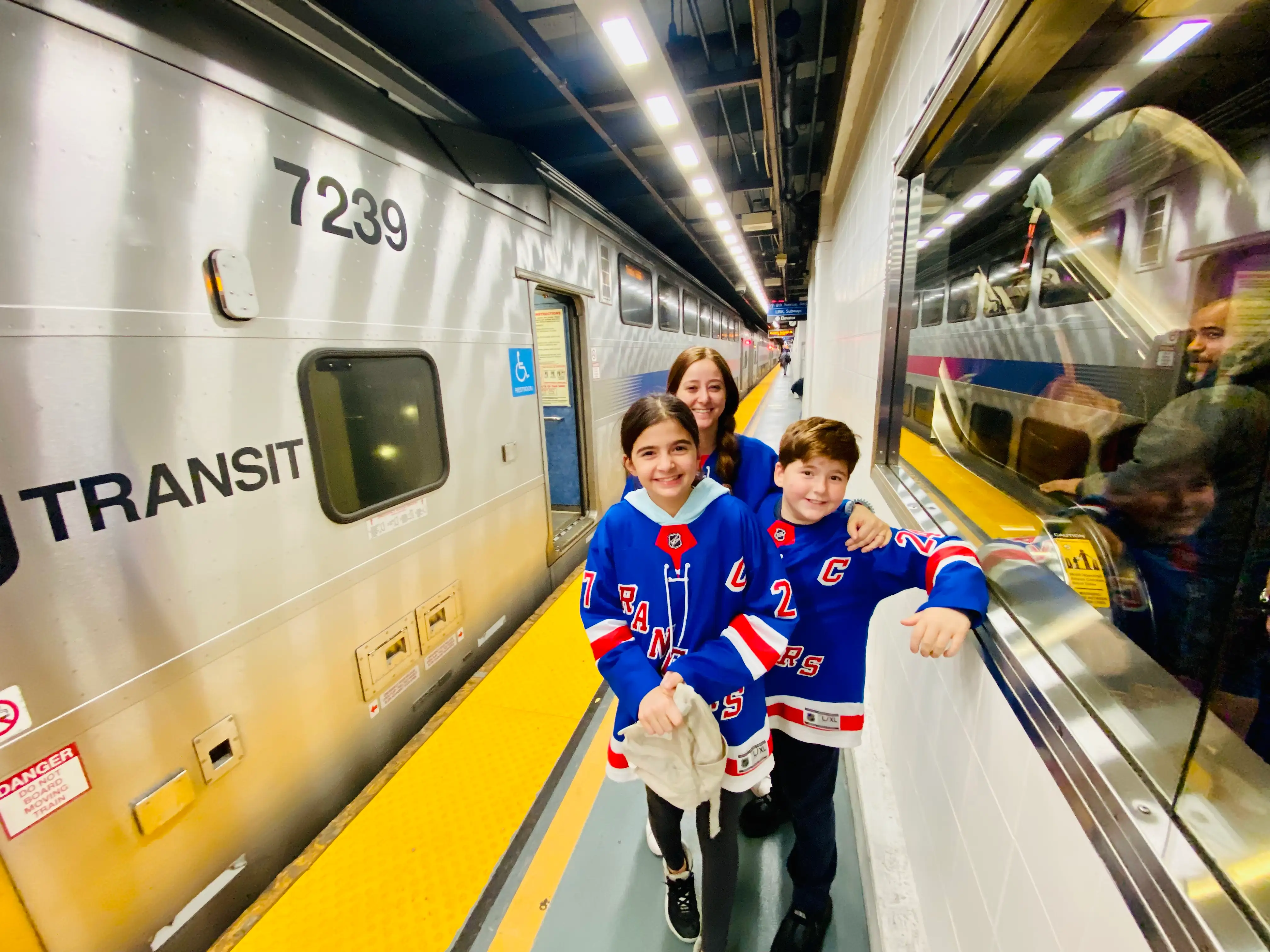 Family in NY rangers jerseys standing next to subway train