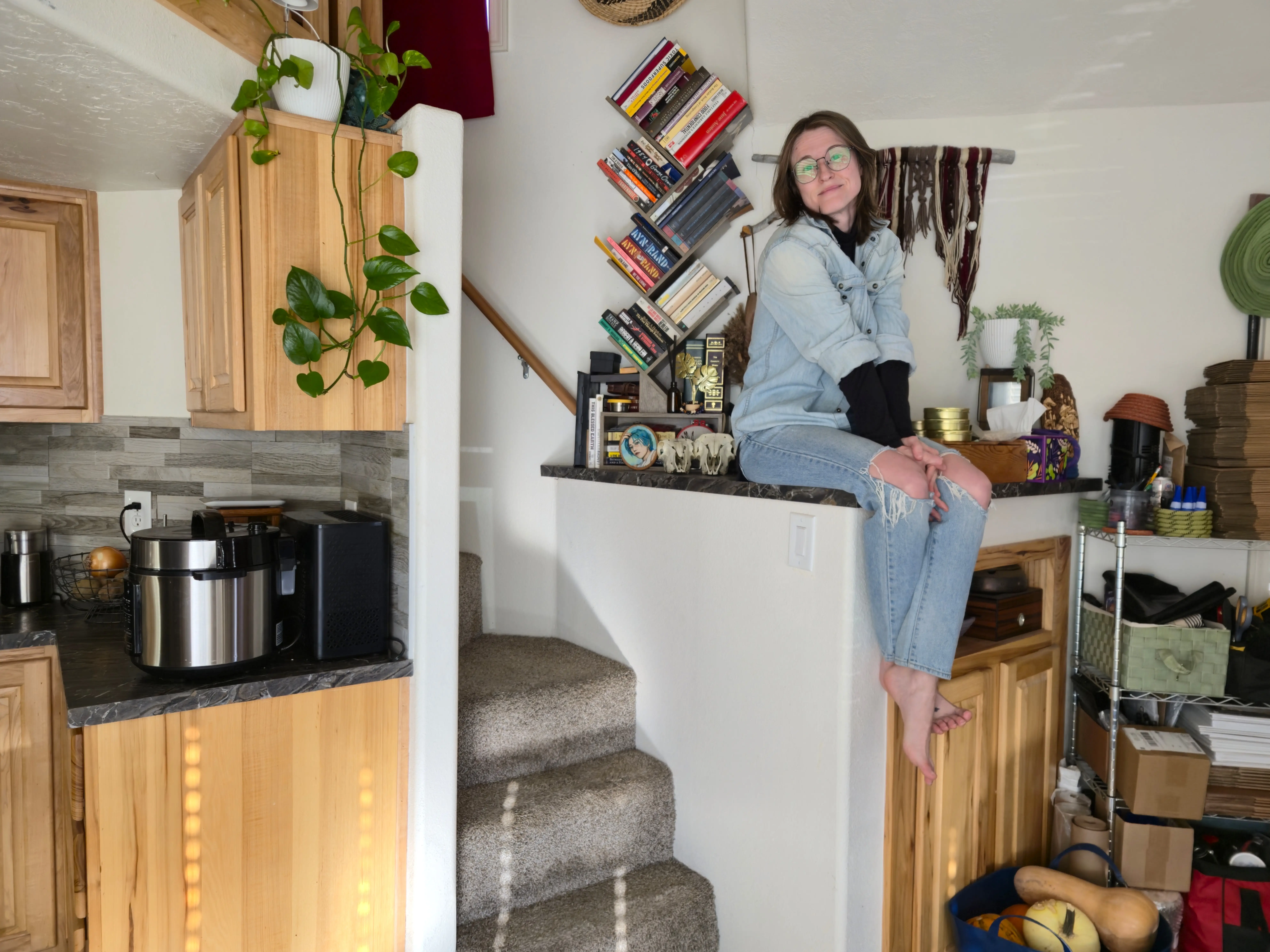 author Amber McDaniel sitting on ledge near books, shelving in tiny home