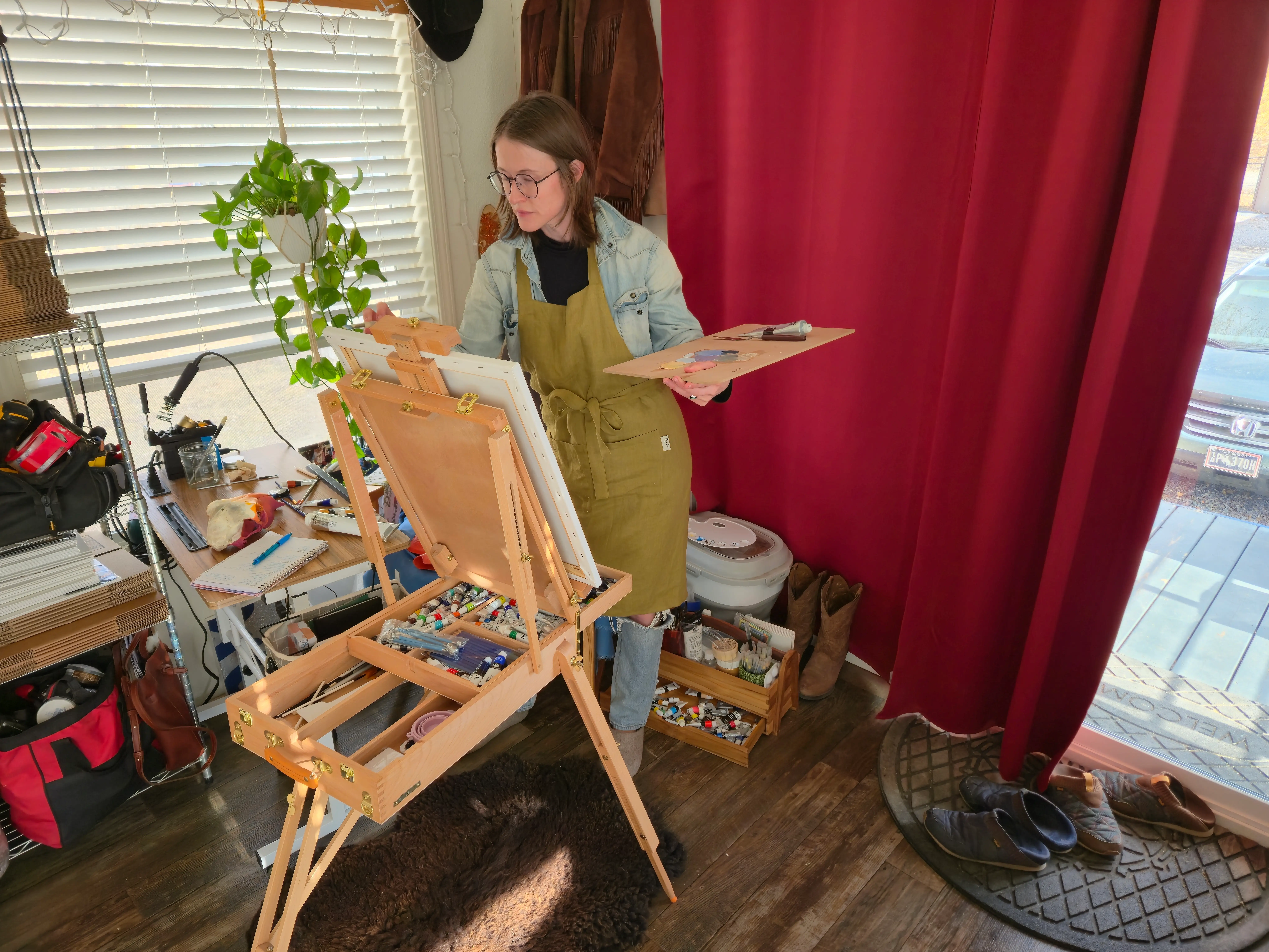 woman painting at canvas in front of red curtain