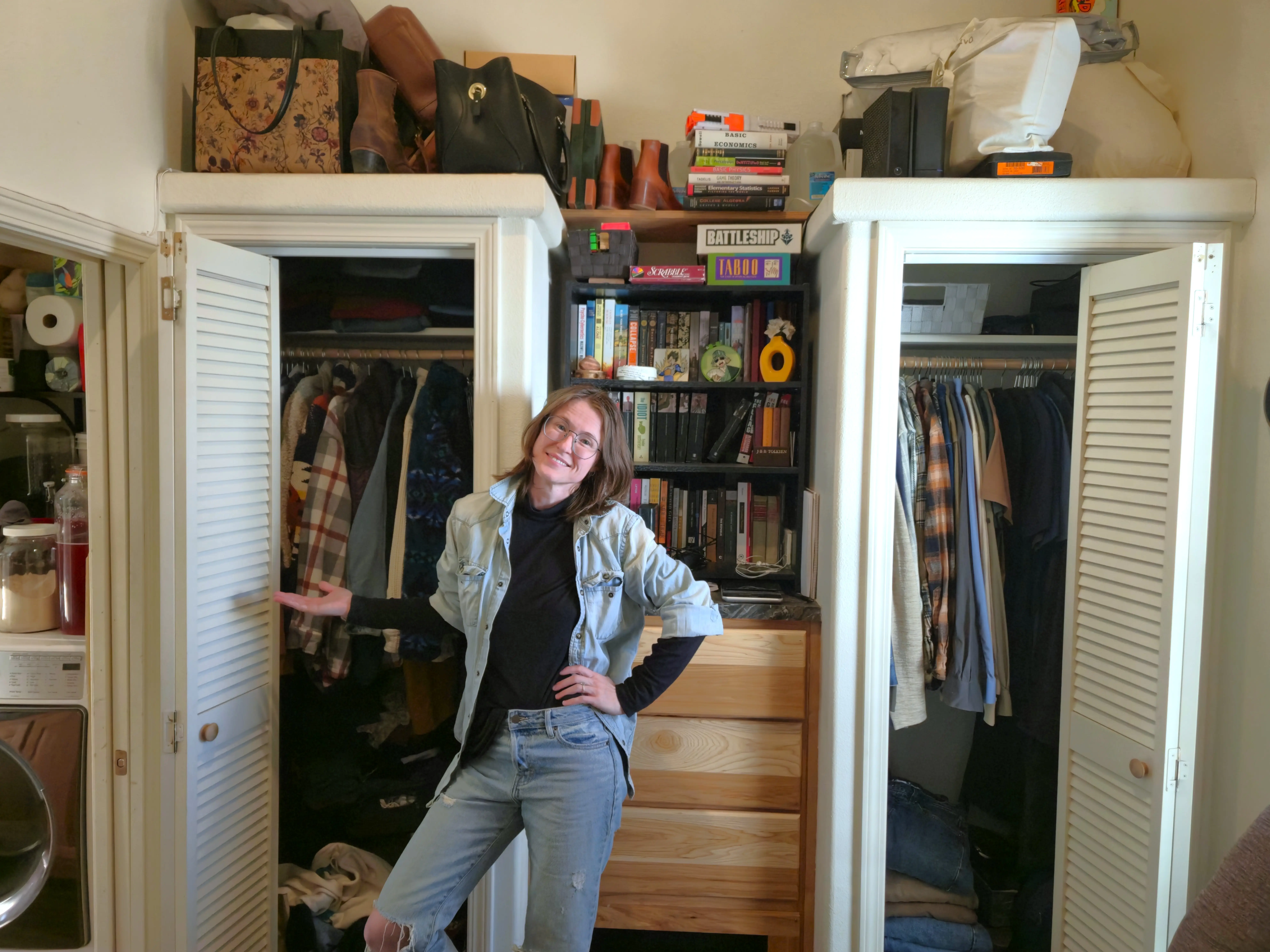 Author Amber McDaniel standing with two closets with doors open and shelving, dresser between them
