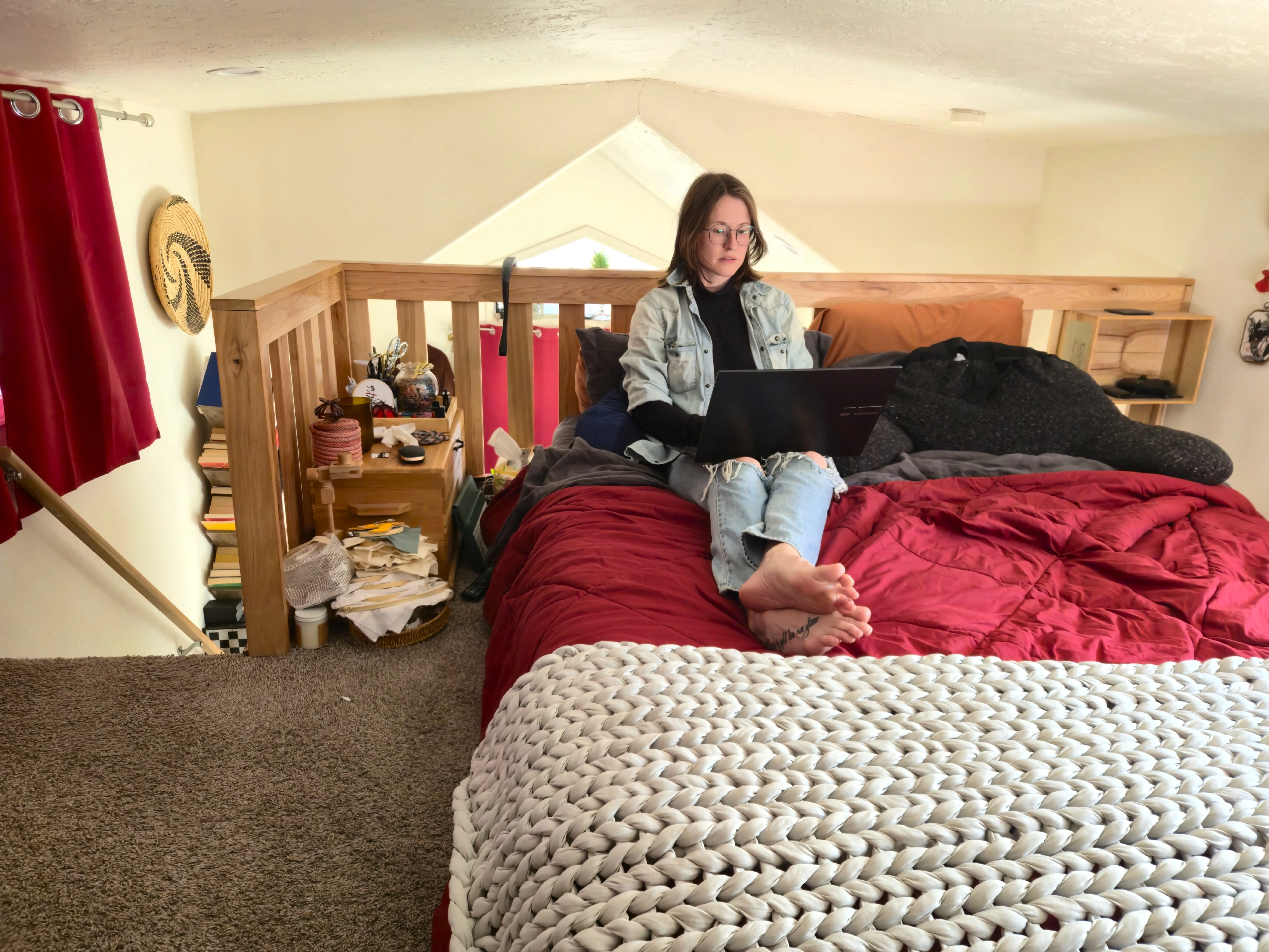 Author Amber McDaniel sitting on lofted bed while working on laptop