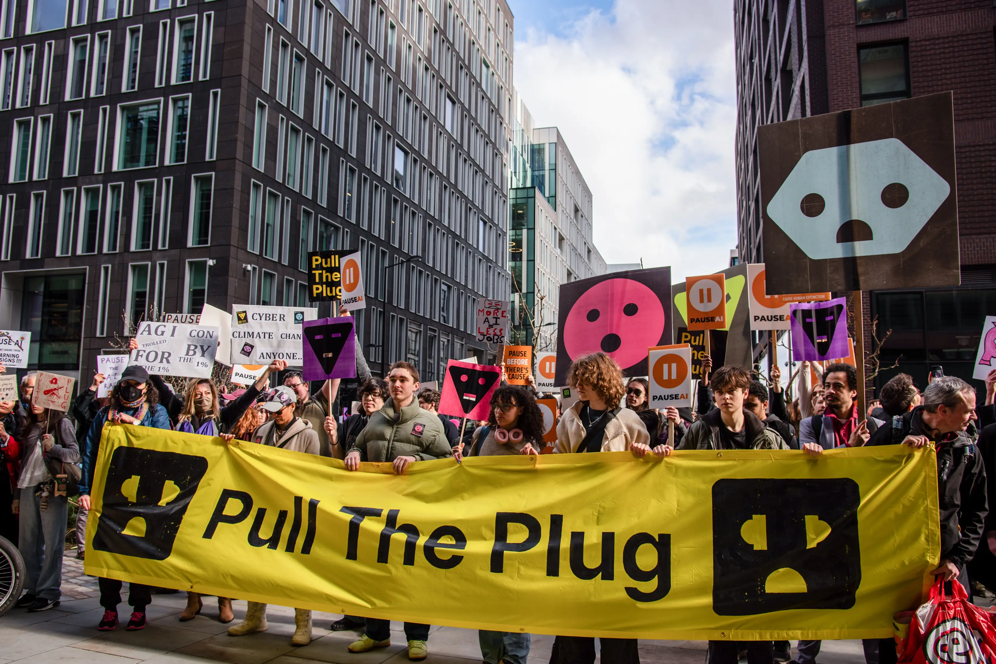 Protestors hold placards and a large banner during the 