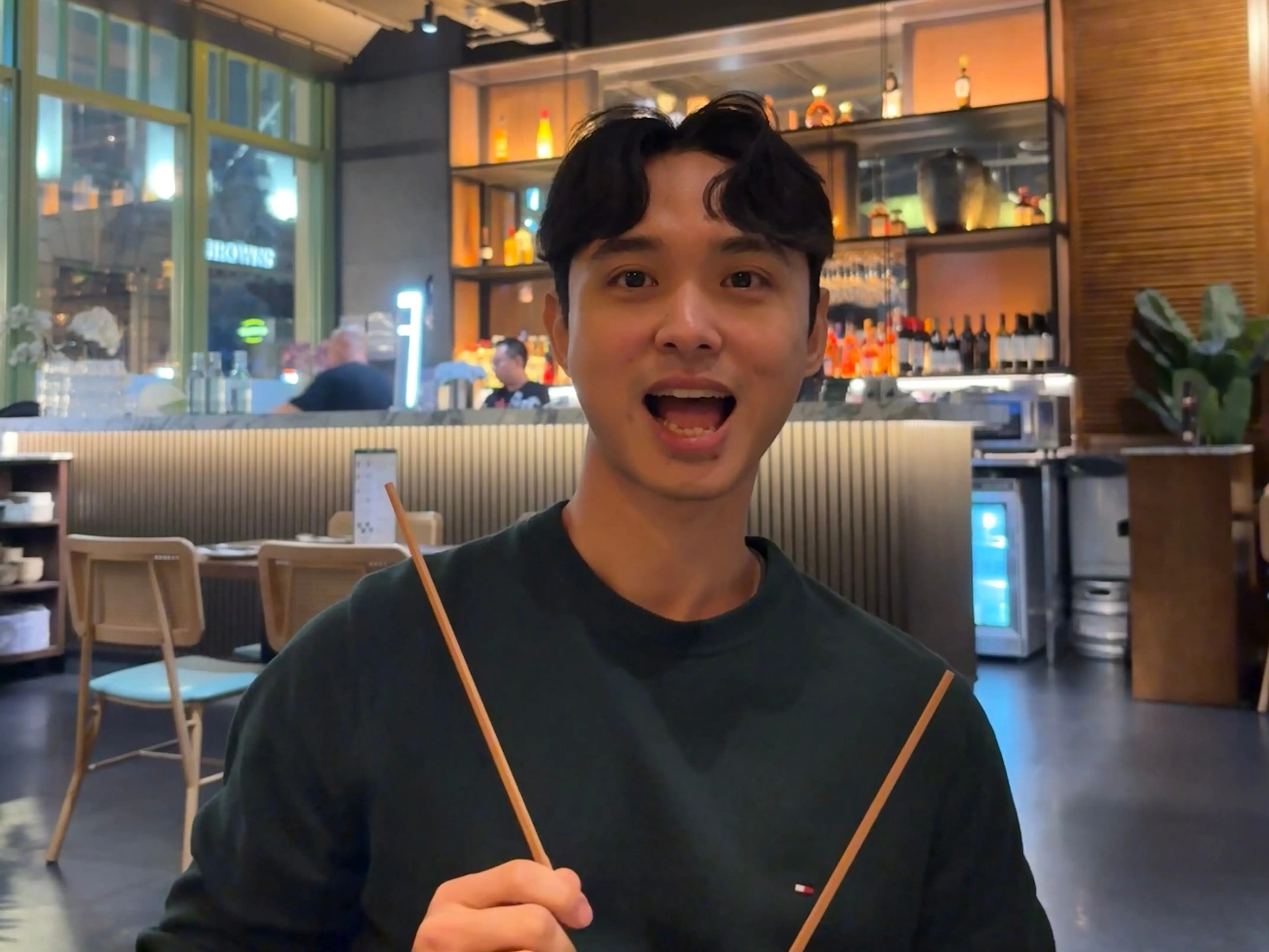 Jack Kim at a restaurant holding chopsticks.