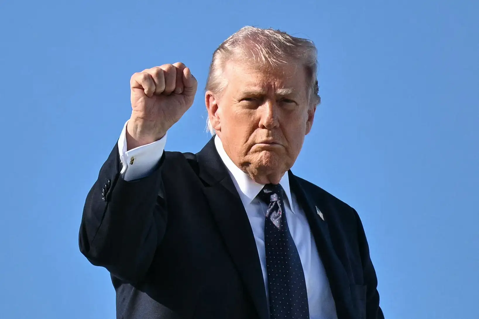 President Donald Trump forms a fist and holds it in the air before he boards Air Force One.