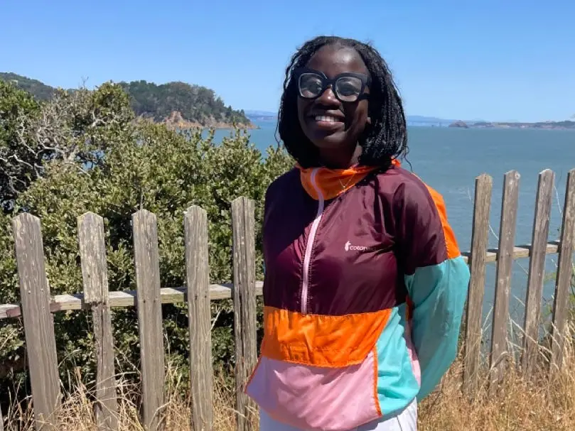 Author Alicia Simba smiling in windbreaker at beachy area