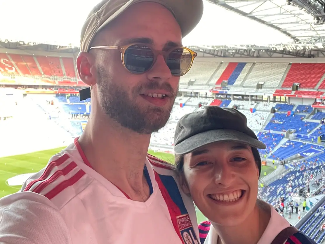 The writer and her husband posing in the bleachers at a sporting event.