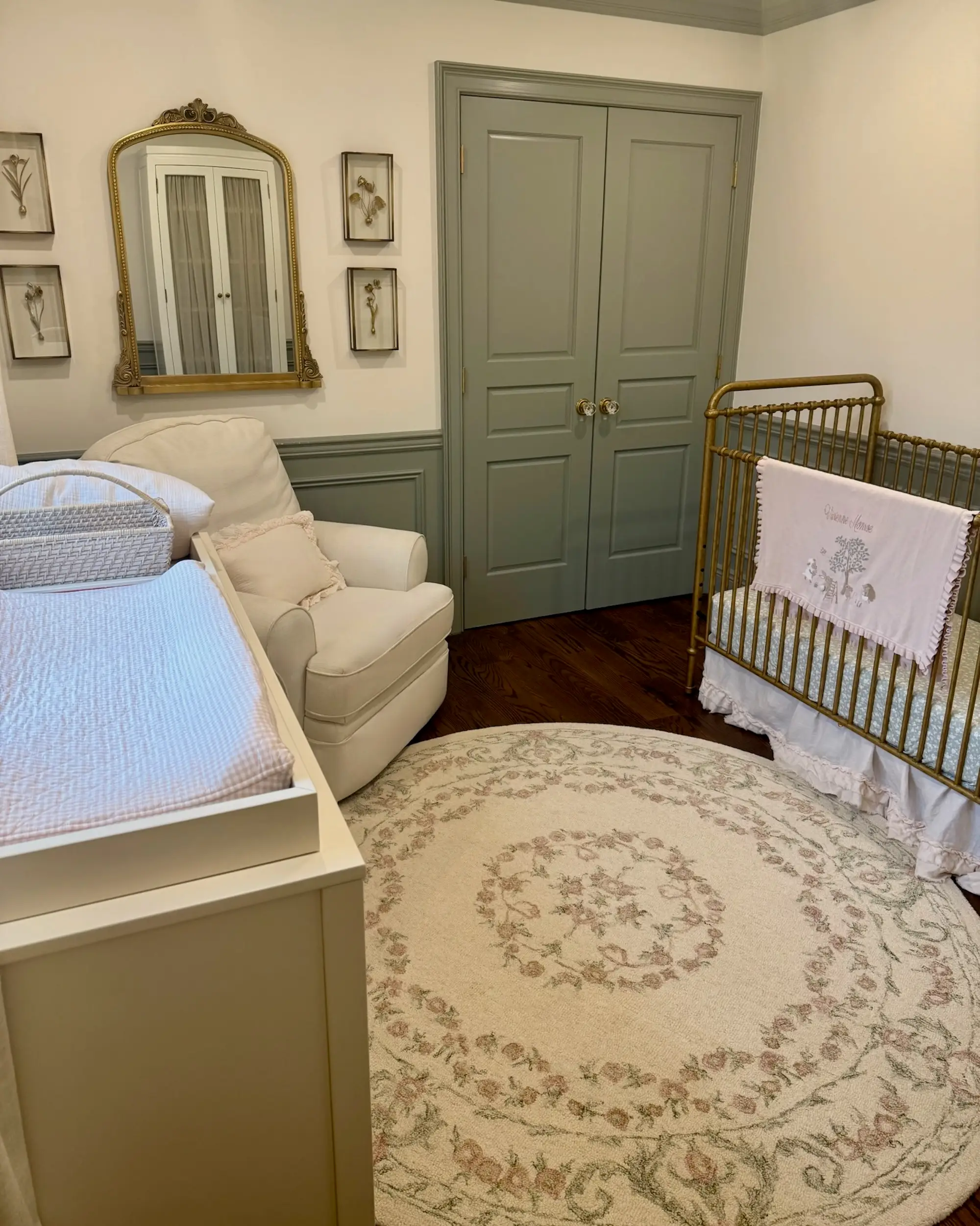 A nursery with a crib, chair, and changing table. A green closet sits on one wall.